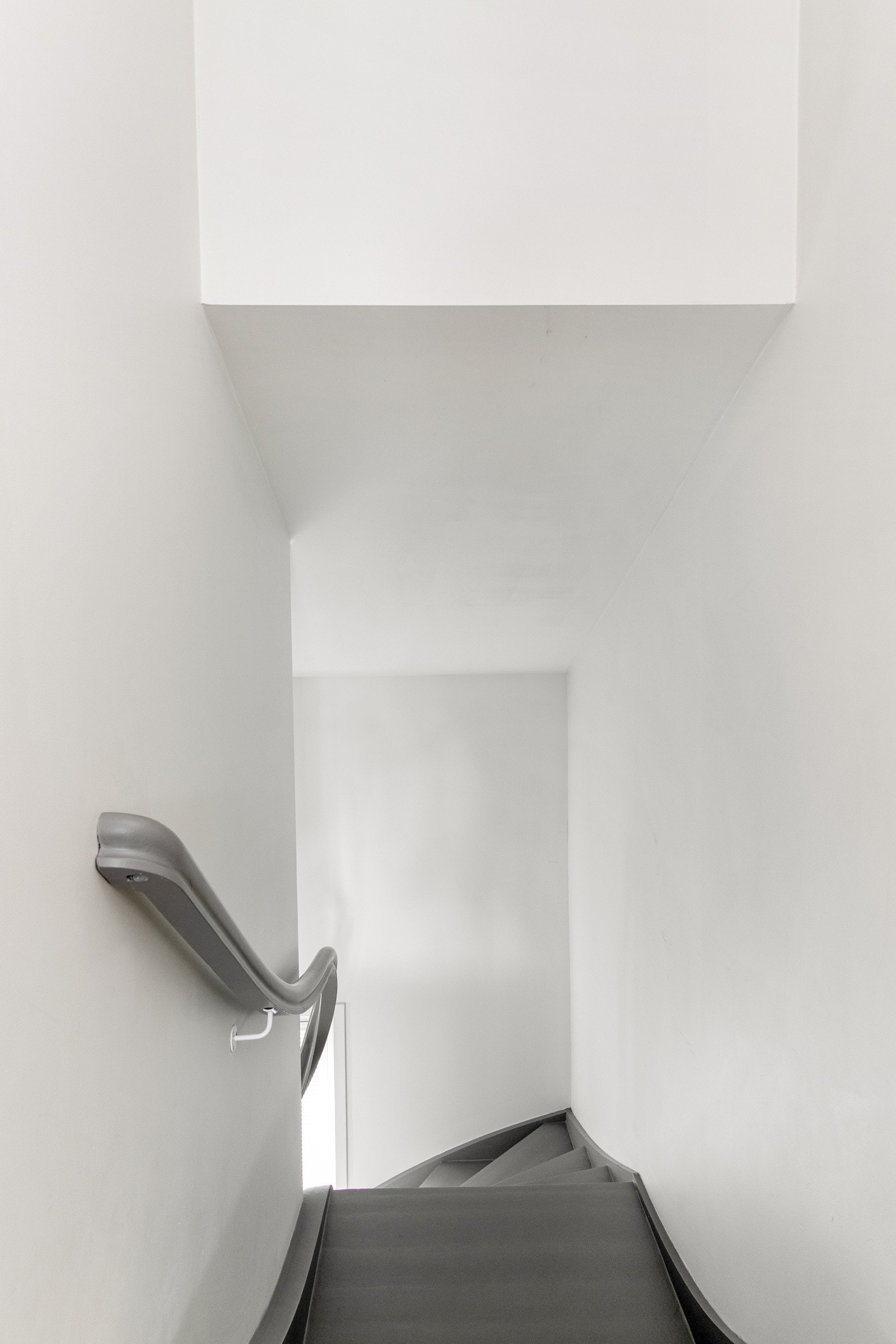 Fra entreen er det en gråmalt tretrapp som leder opp til gangen andre etasje, et pent rom med parkettgulv, hvite vegger og downlights. Galleribilde