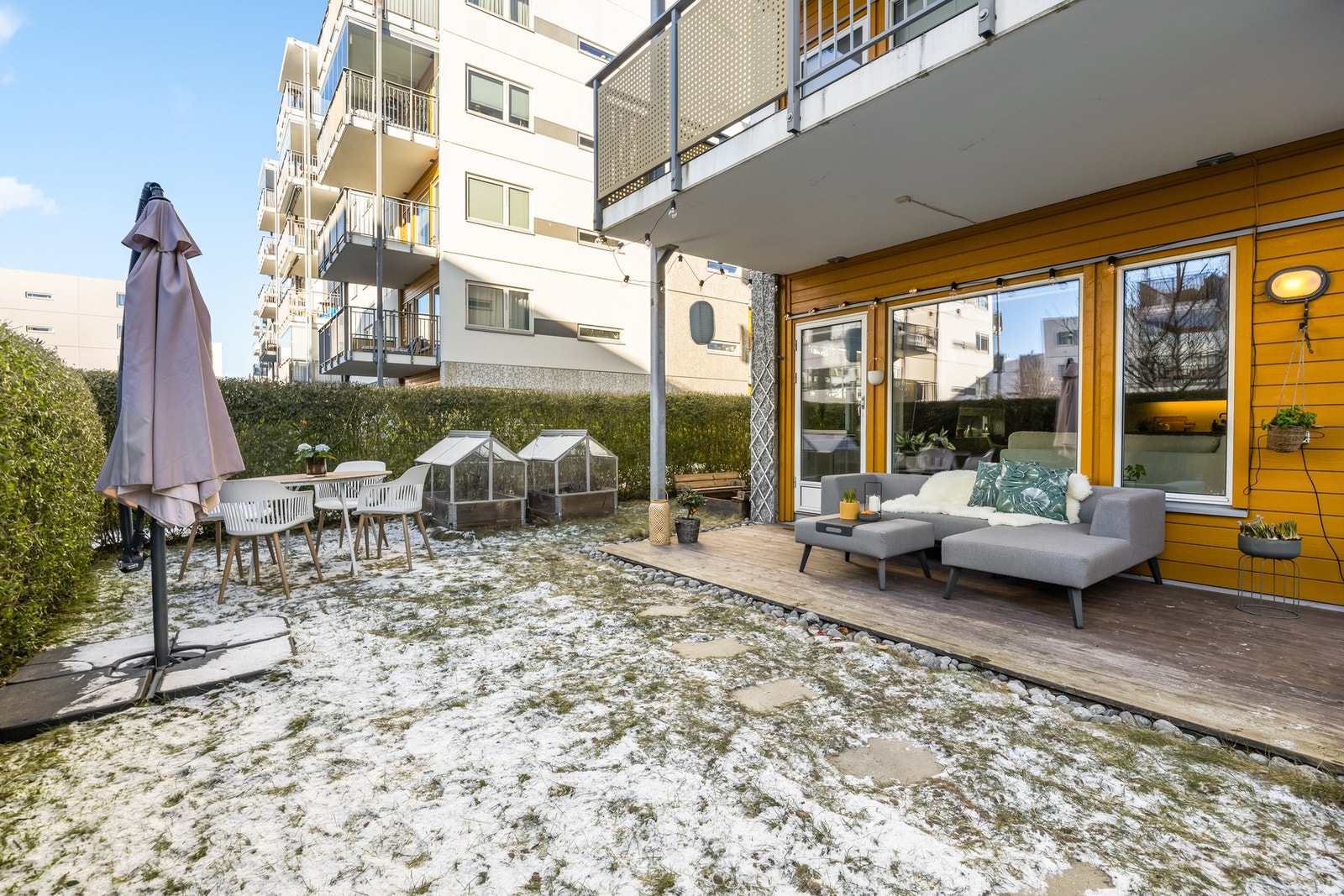 Lys og trivelig uteplass med terrasse og plen. Området er skjermet av tett og høy hekk og ligger i et moderne boligkompleks. Galleribilde