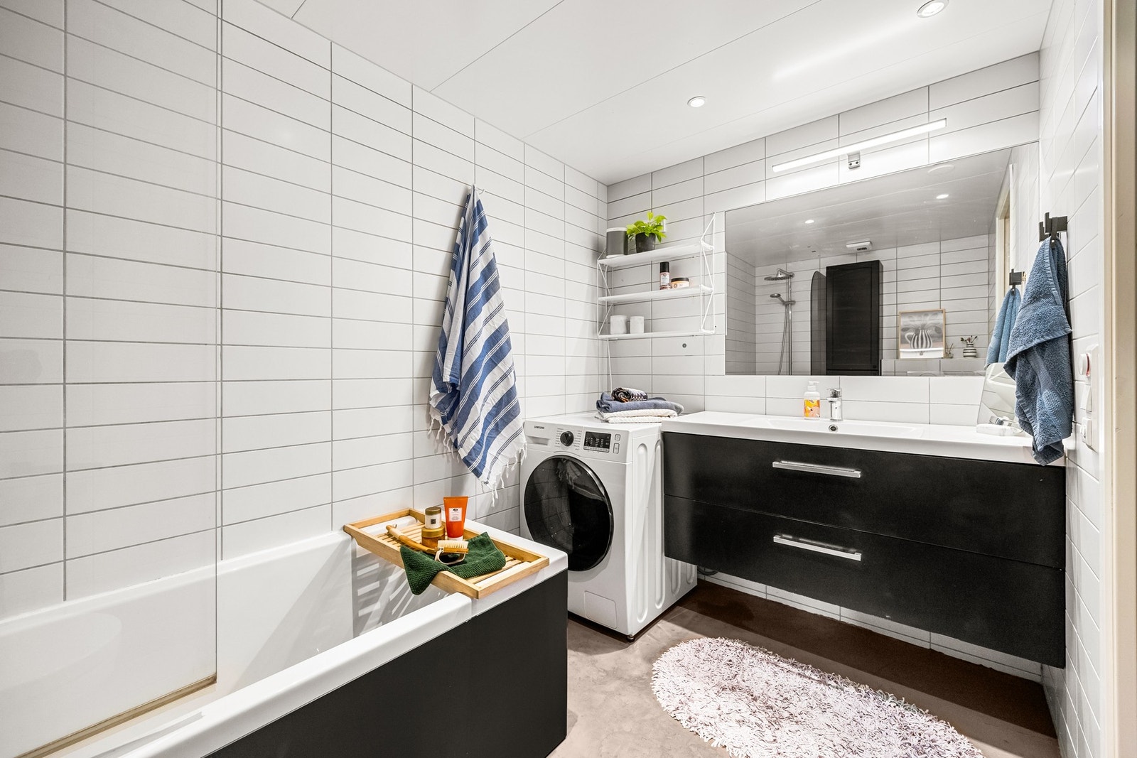 Badet i denne leiligheten har et oppgradert og moderne uttrykk, med flislagte veggflater og mikrosement på gulvet. Rommet er utstyrt med termostatstyrte varmekabler, noe som sikrer behagelig temperatur året rundt. Galleribilde