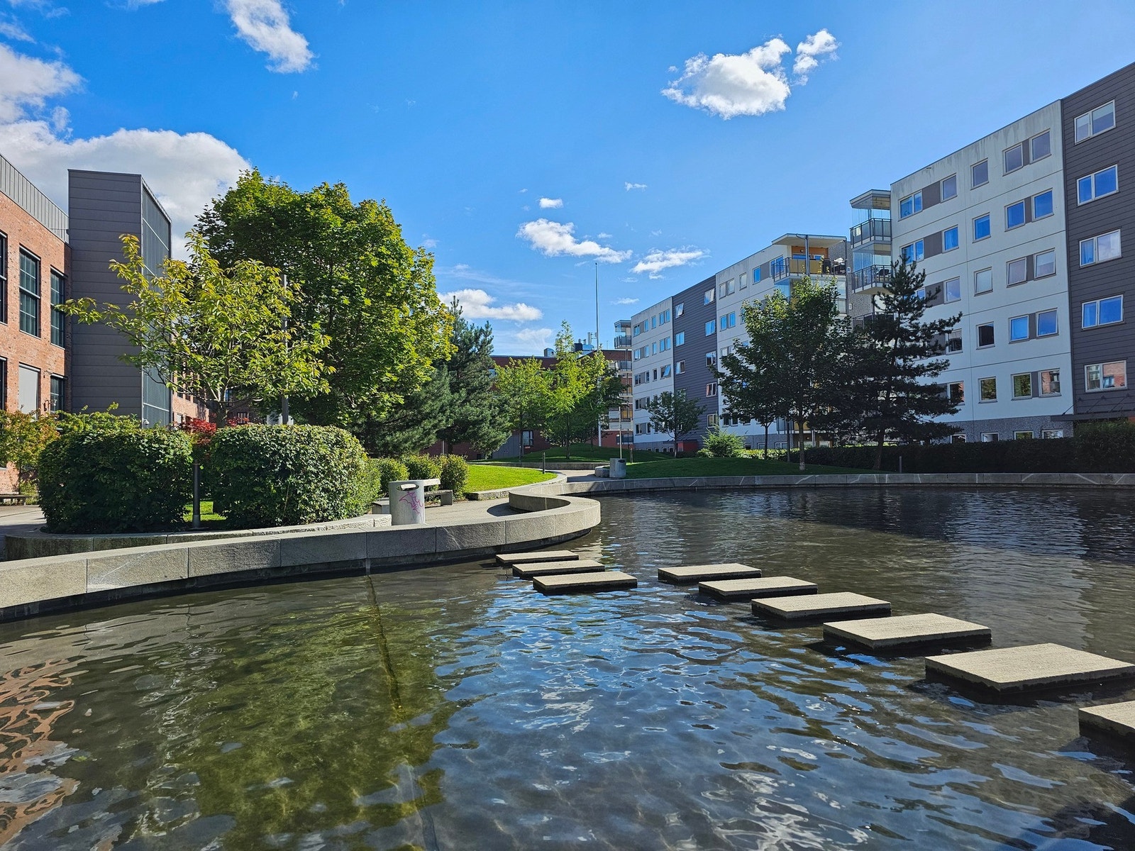 Et moderne boligområde med grønne trær, busker og vannspeil. Galleribilde