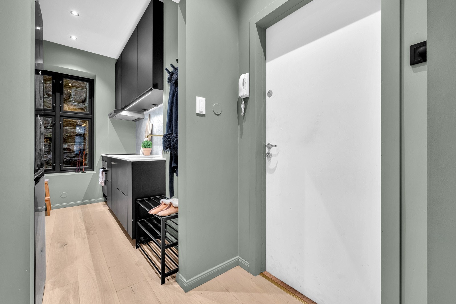 Ved inngangsdøren er en portelefon montert, samt garderobeskap langs den ene veggen; plassbygd og holdt i samme fargetone som veggene Galleribilde