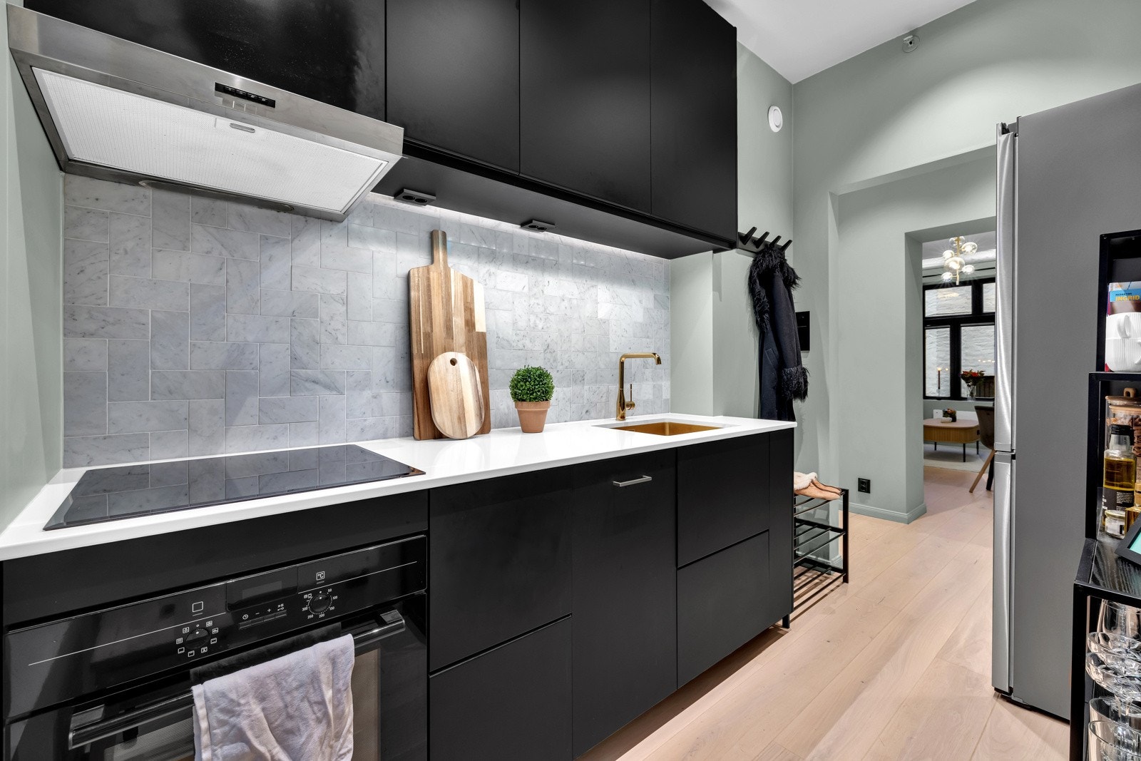 Innenfor entreen har leiligheten et lekkert kjøkken fra 2021 med integrert stekeovn, induksjonstopp og smal oppvaskmaskin Galleribilde