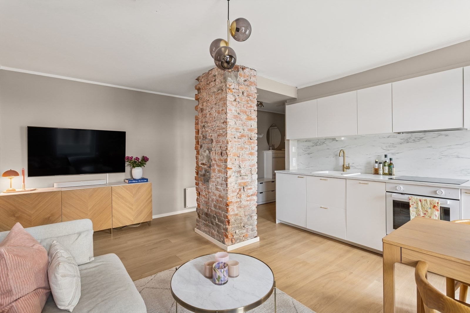 Vakker teglsteinspipe midt i stuen. Denne fungerer fint som en romdeler og setter en særegen detalj Galleribilde