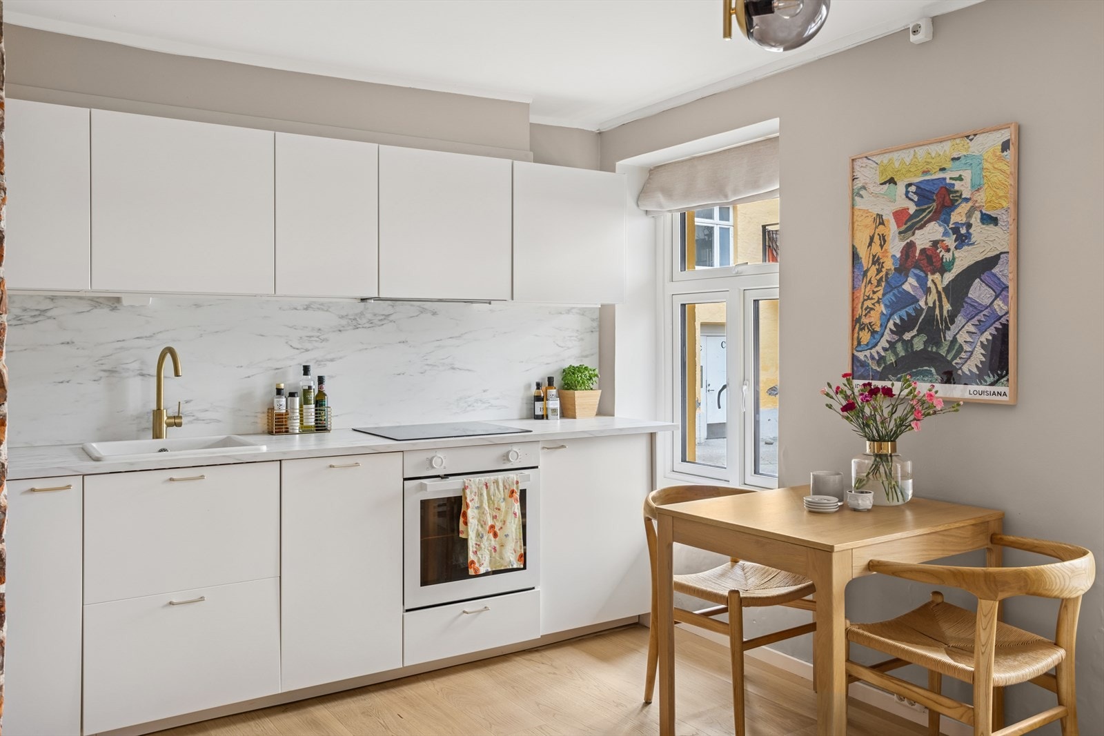 Kjøkkeninnredningen har slette lakkerte fronter, laminat benkeplate med sprutplate over, enkel keramisk oppvaskkum og kjøkkenventilator i stål ført til kanal Galleribilde