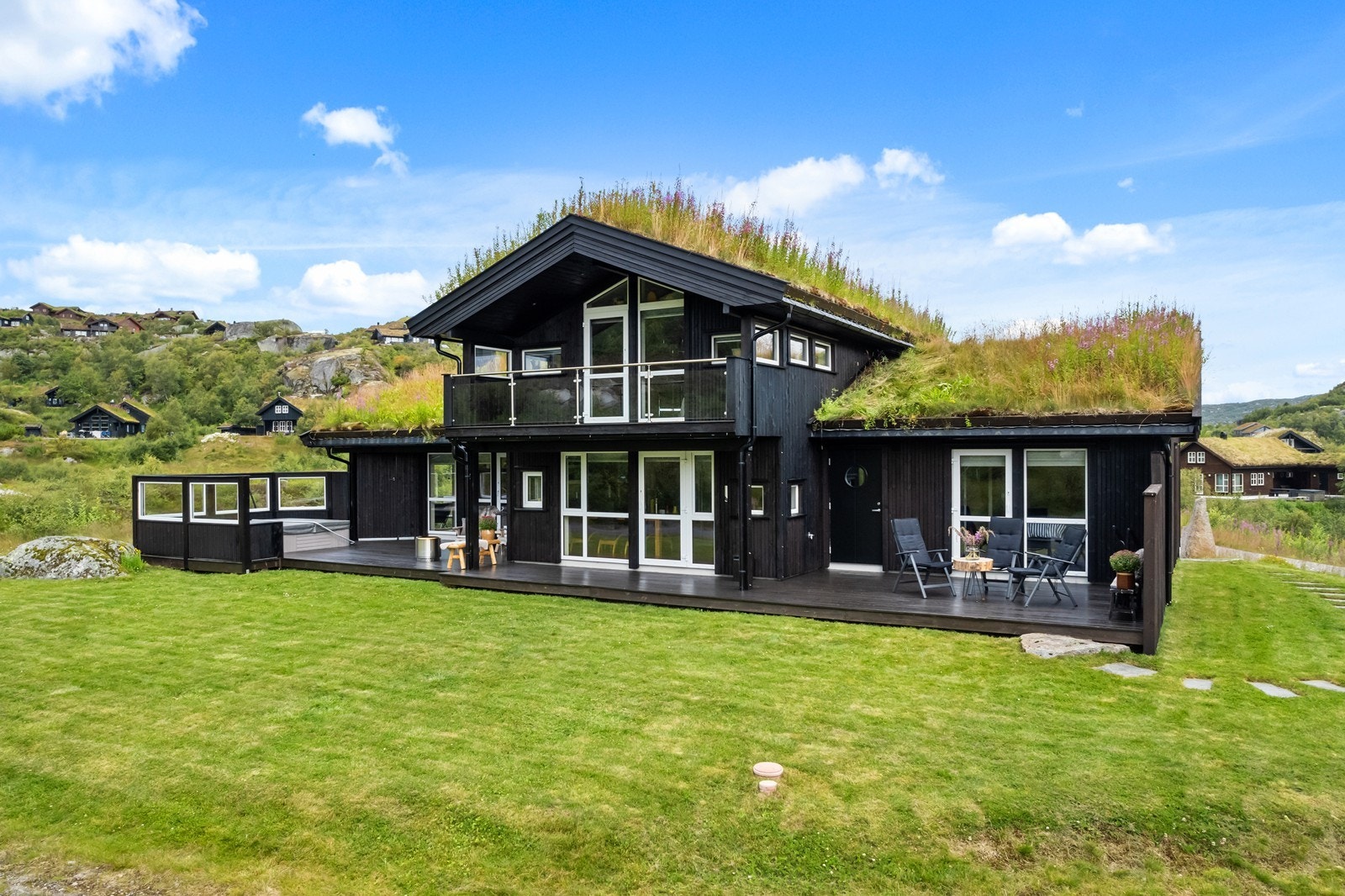 Hytten er meget flott med moderne løsninger som glassrekkverk, store vindusflater og terrasse med direkte tilgang til plenen Galleribilde
