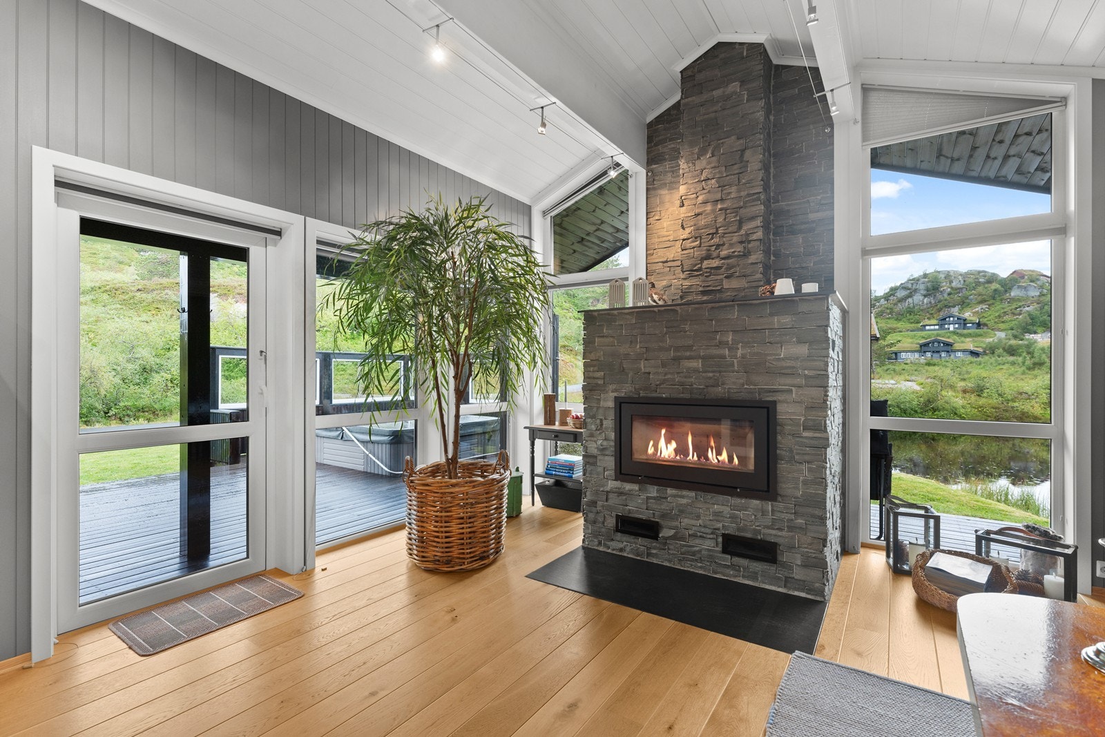 Peisen i stuen er som et smykke - pent innreammet at de store vindusflatene - her er det god kontakt med inne og uteområdene Galleribilde