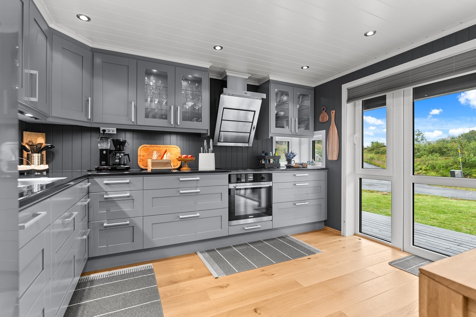 Kjøkkenet har en lekker innredning med mye skapplass, gode arbeidsflater og vinduer med skyvedør langs den ene veggen Galleribilde