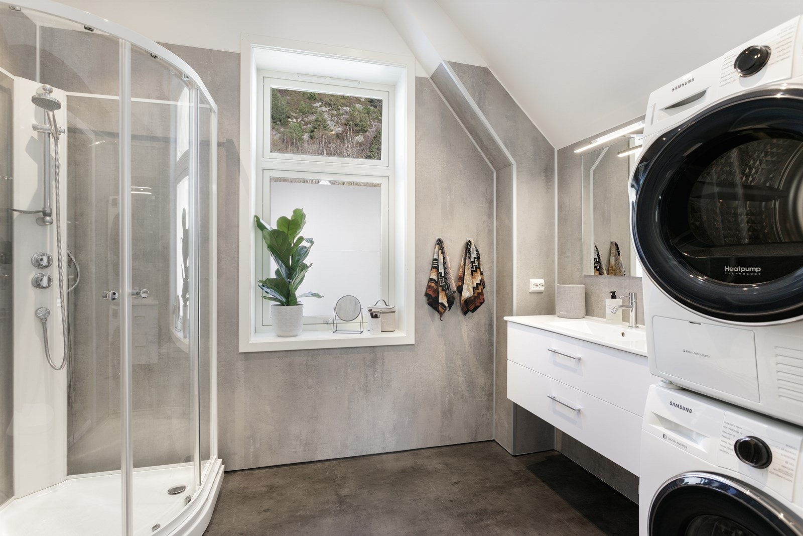 Badet er innredet med dusjkabinett, servant, vegghengt toalett og opplegg for vaskemaskin. Galleribilde