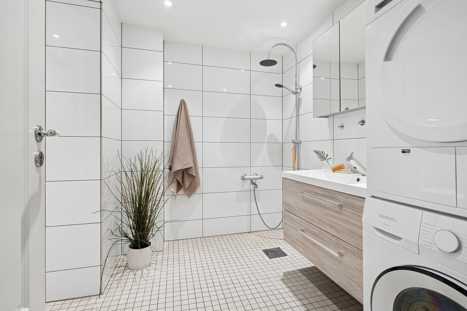 Badet er romslig og inneholder to dusjhjørner, servant med skuffer, speilskap, wc og opplegg til vaskemaskin og tørketrommel. Galleribilde