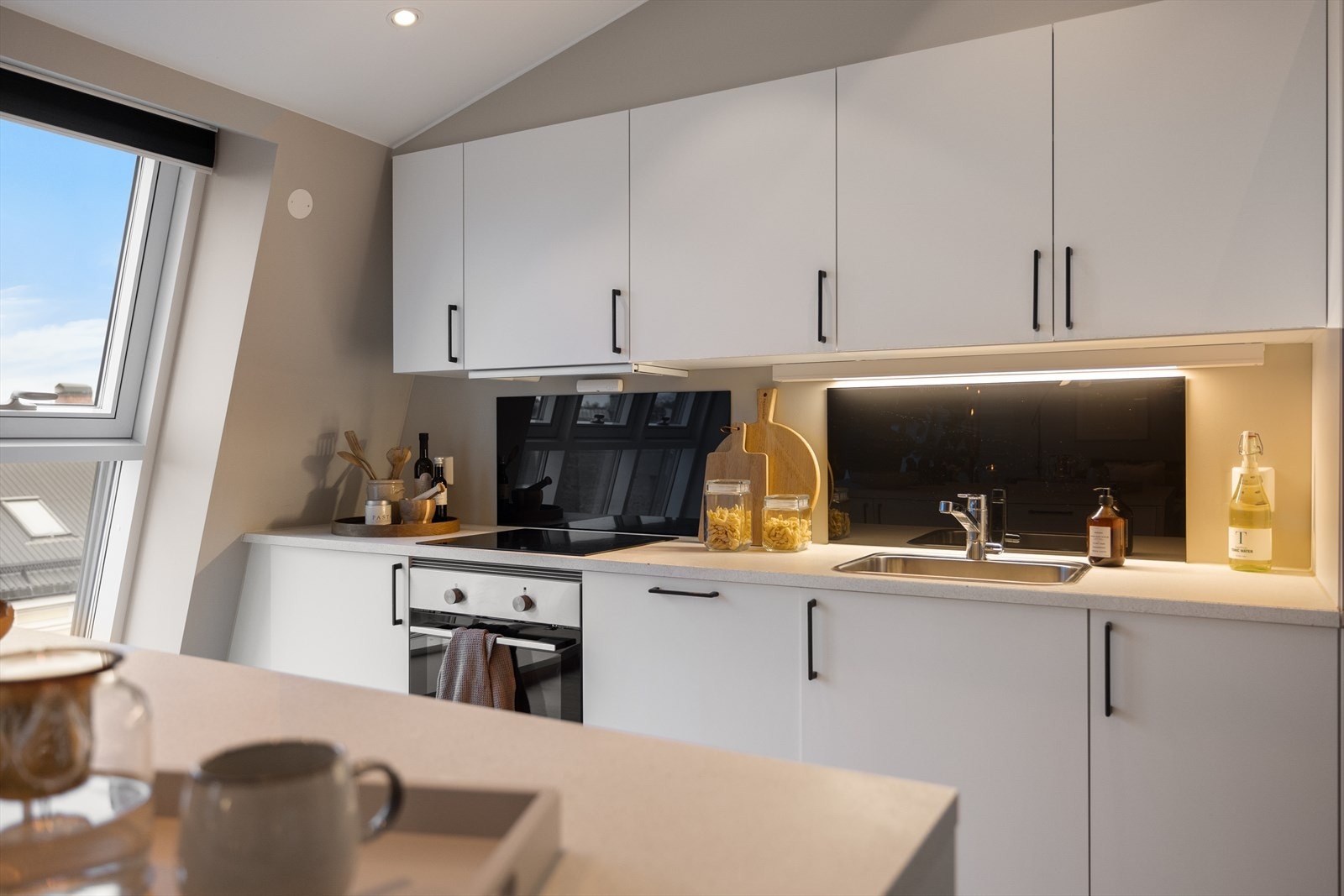 Tidsriktig glatt innredning, soft close, armatur, nedfelt stålkum og induksjonstopp, integrert komfyr, oppvaskmaskin og kjøl/frys Galleribilde