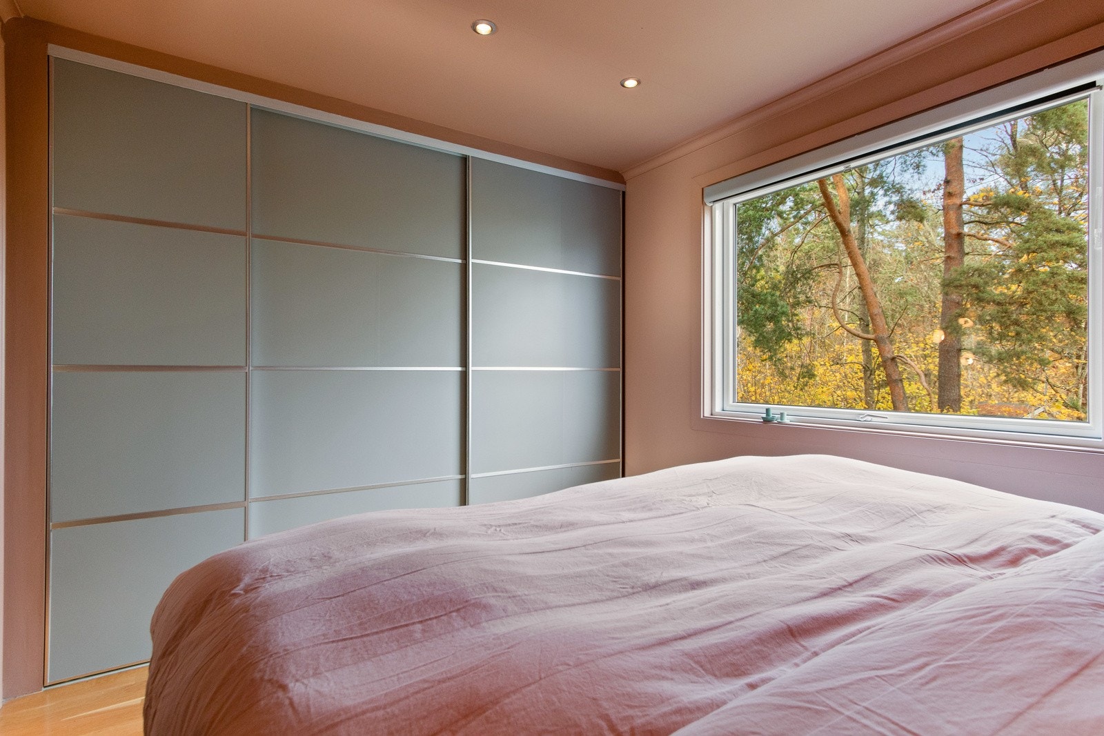 Den ene veggen dekkes med skyvedørsgarderobe med frostede fronter og gir gode oppbevaringsmuligheter. Galleribilde