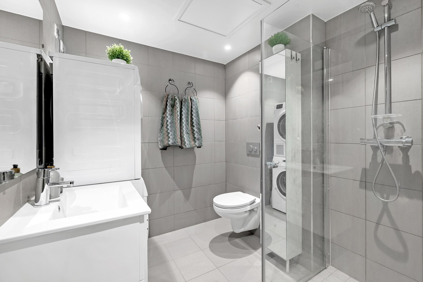 Moderne bad med store fliser i naturfarger og med vannbåren gulvvarme. Galleribilde