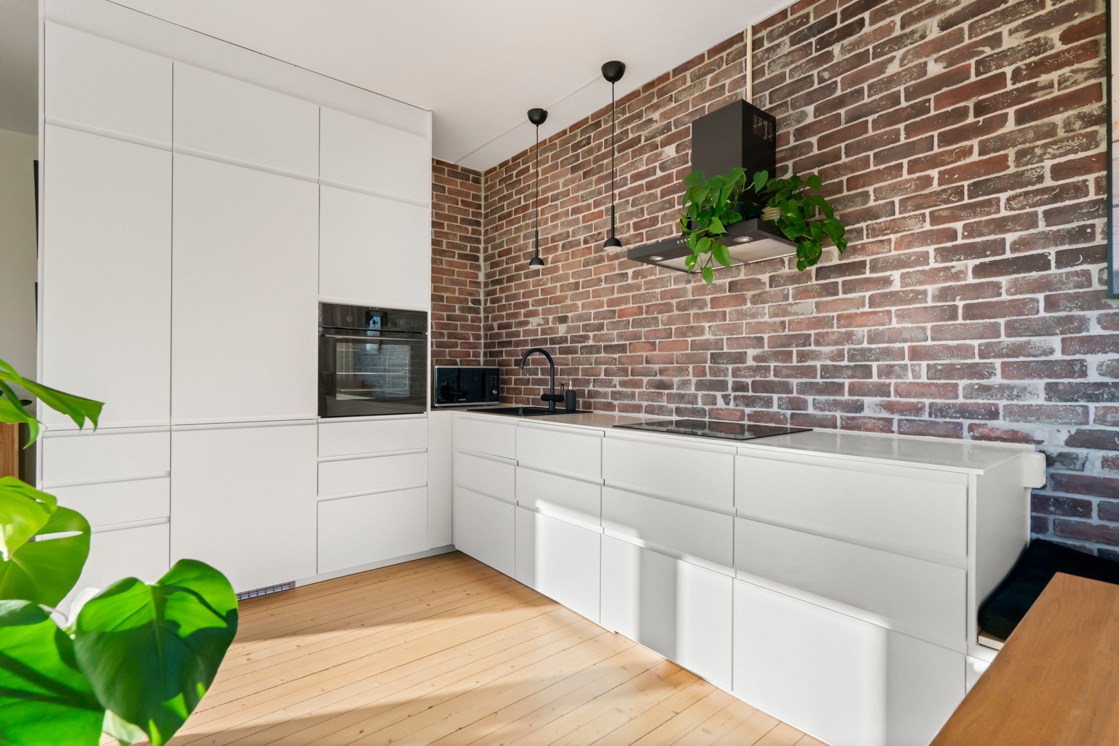 Stilsikkert kjøkken fra 2016 med lys innredning og lekker kompositt benkeplate. Kjøkkenet er plassert i en praktisk L-form med rikelig med skap- og benkeplass. Galleribilde