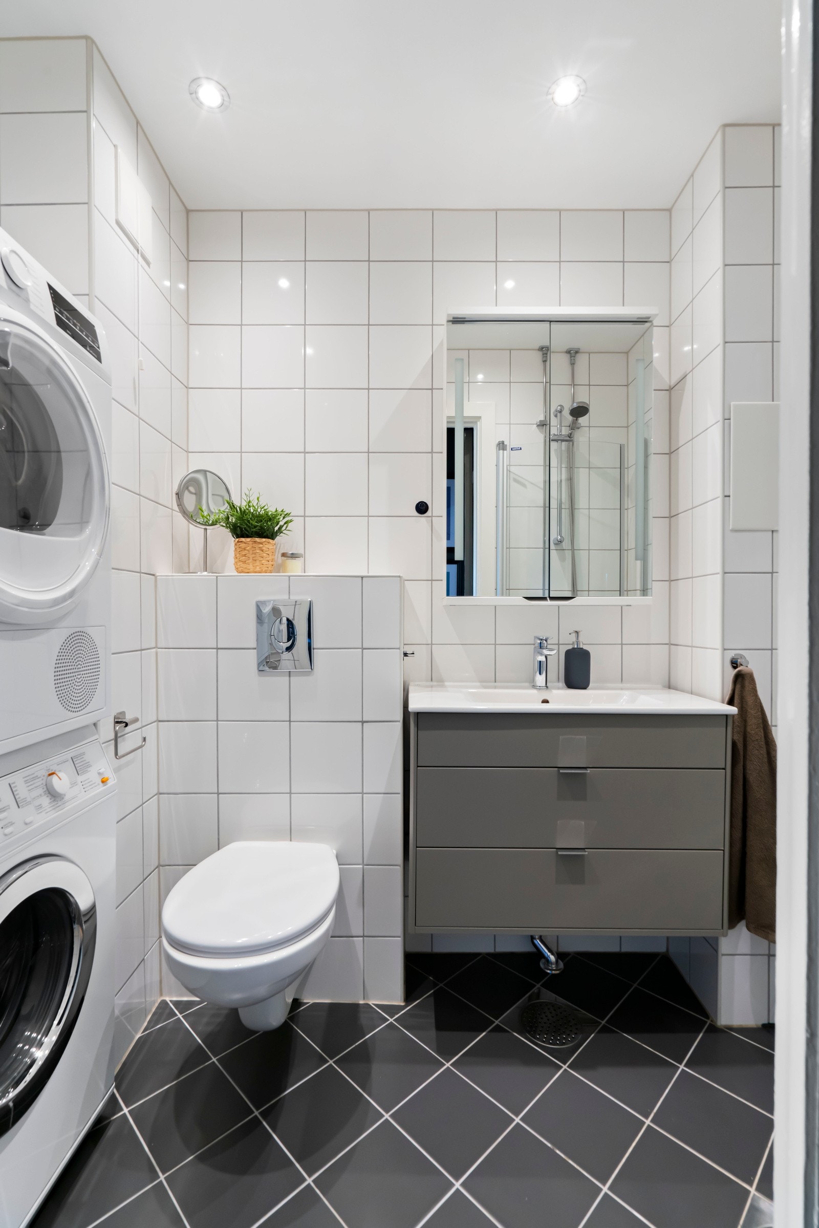 Flott mørk grå servantinnredning med oppbevaringsplass i skuffer. Over servant er et praktisk speilskap med oppbevaringsplass. Avsatt plass til vaskemaskin og tørketrommel i søyle. Galleribilde