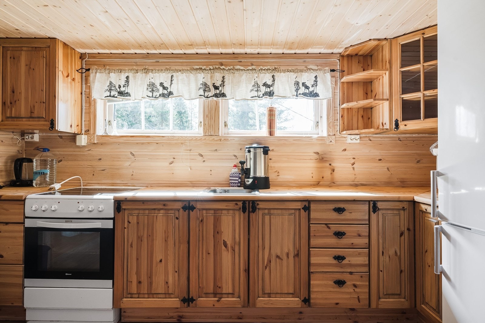 Furu kjøkkeninnredning med profilerte fronter og heltre benkeplate med nedfelt kum. Kjøkkenet har ikke innlagt vann. Hvitevarene medfølger. Galleribilde