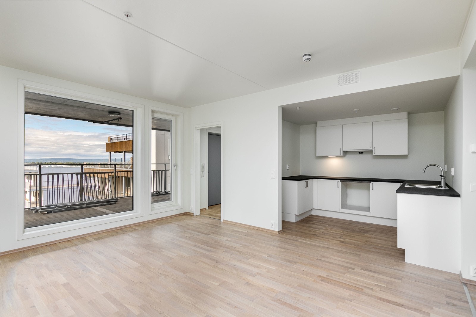 Stilrent og moderne kjøkken i åpen løsning mot stuen. Kjøkkenet har hvite glatte fronter og laminat benkeplate i samt 1-kums vask i rustfritt stål. Avsatt plass til hvitevarer Galleribilde