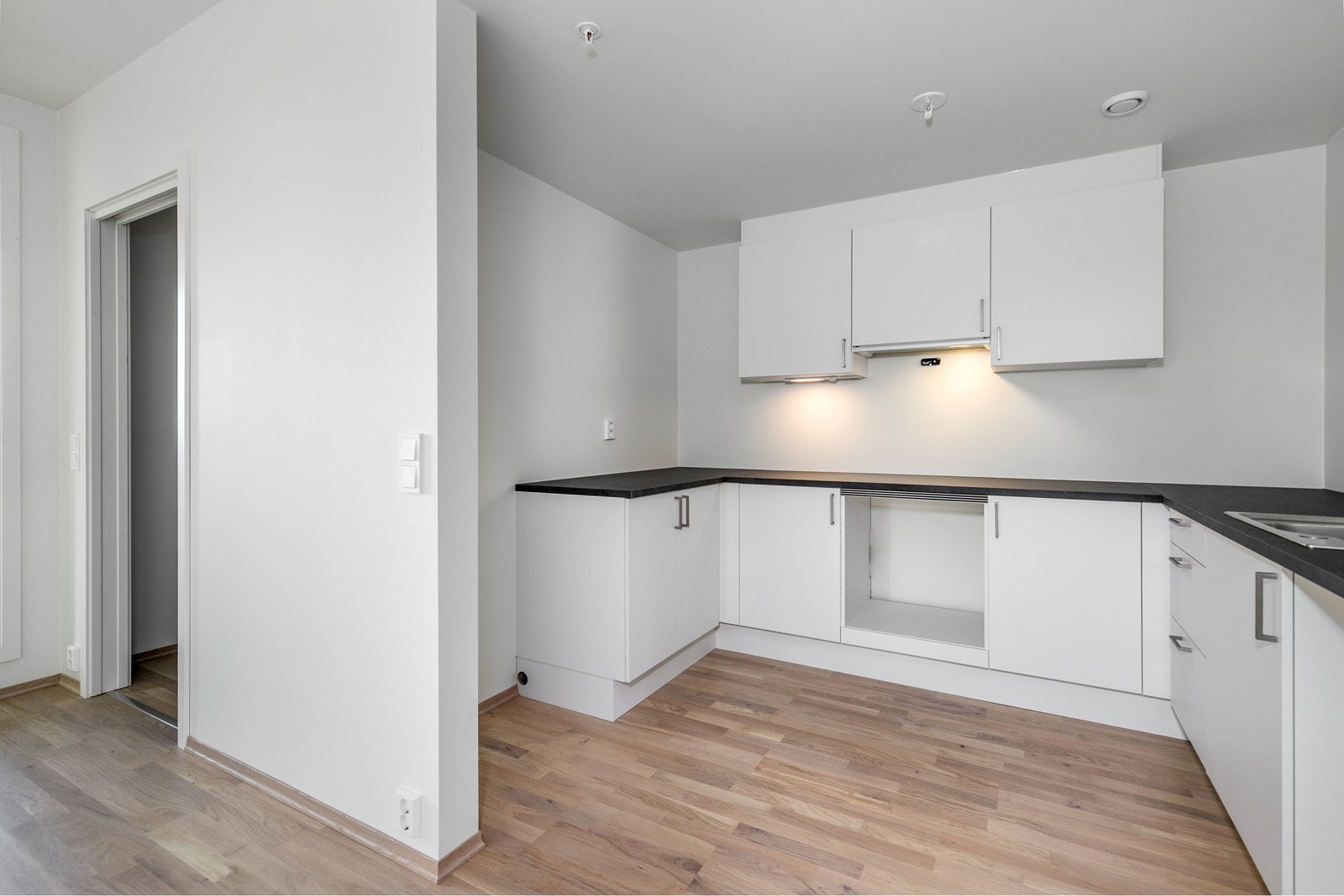 Stilrent og moderne kjøkken i åpen løsning mot stuen. Kjøkkenet har hvite glatte fronter og laminat benkeplate i samt 1-kums vask i rustfritt stål. Avsatt plass til hvitevarer Galleribilde