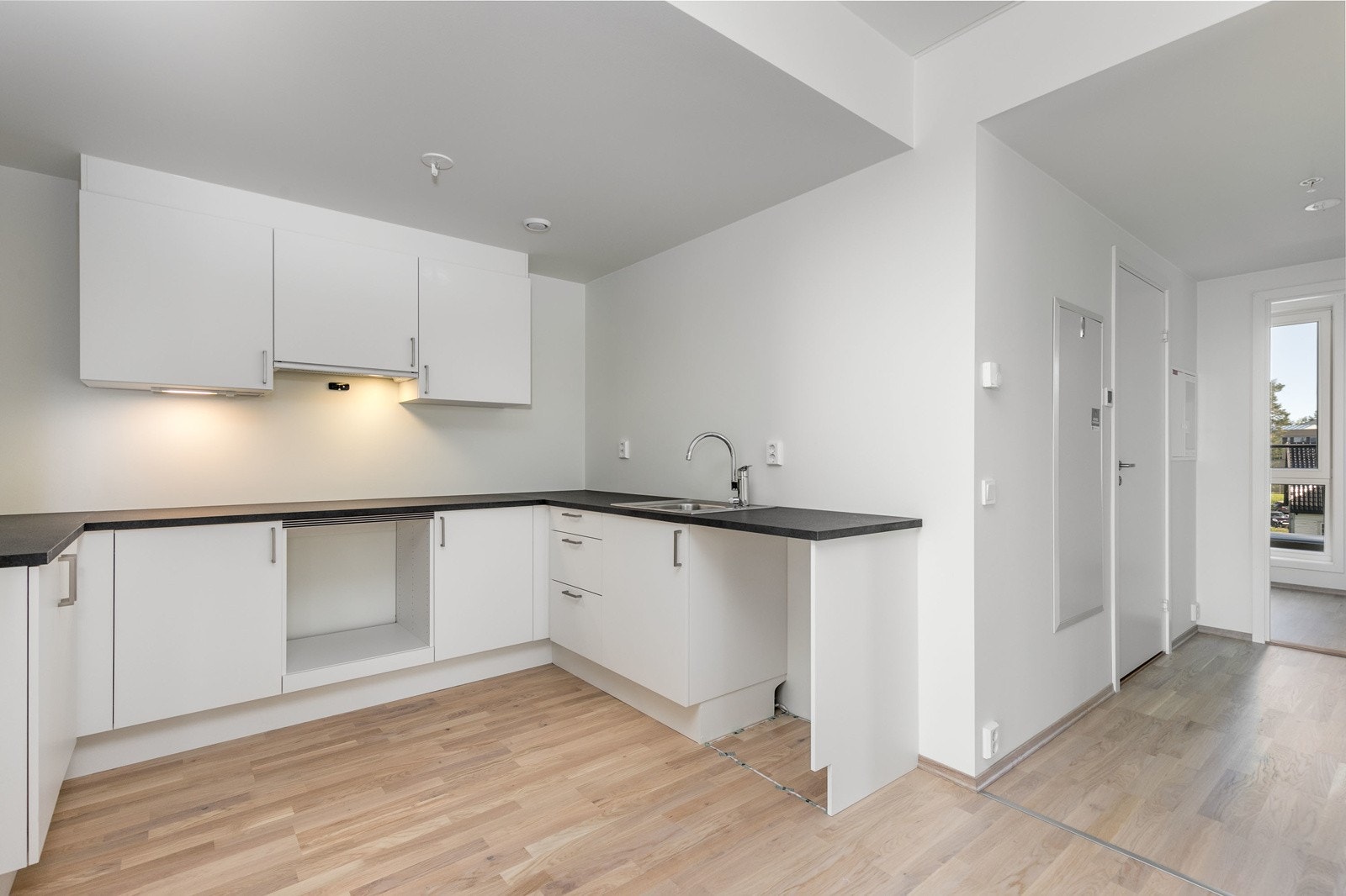 Stilrent og moderne kjøkken i åpen løsning mot stuen. Kjøkkenet har hvite glatte fronter og laminat benkeplate i samt 1-kums vask i rustfritt stål. Avsatt plass til hvitevarer Galleribilde