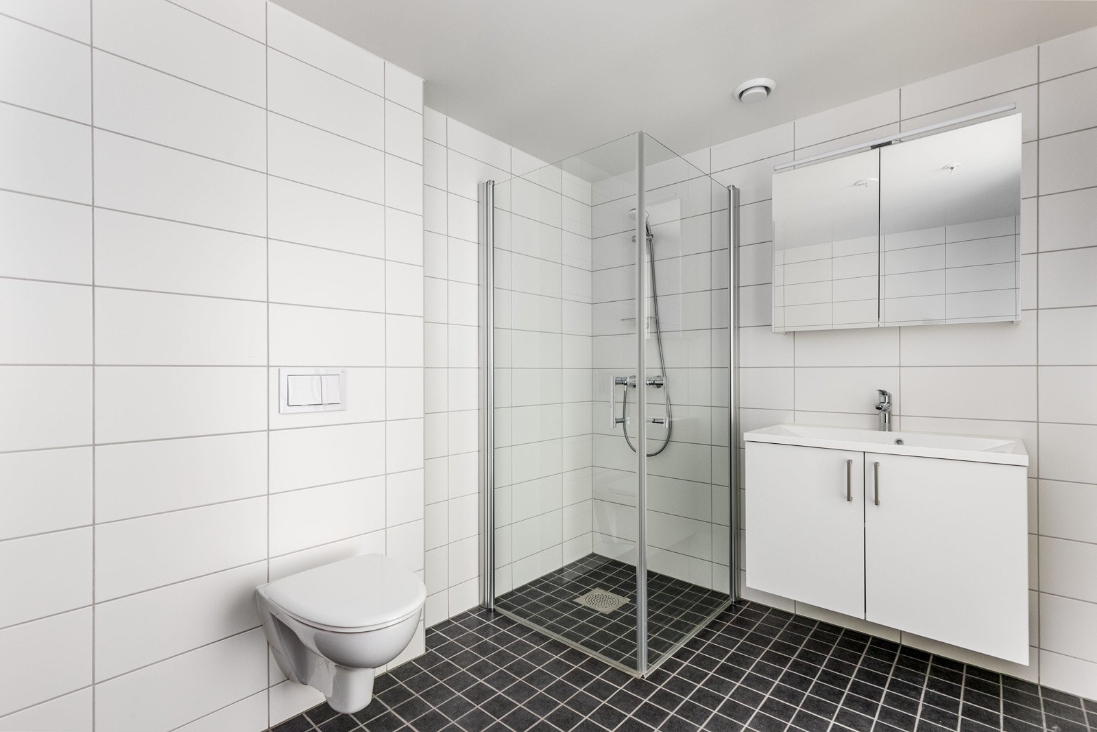 Pent bad med flislagte overflater og varme i gulv. Innredning på bad består av moderne skuffeinnredning med servant, samt speil med belysning over servant. Galleribilde