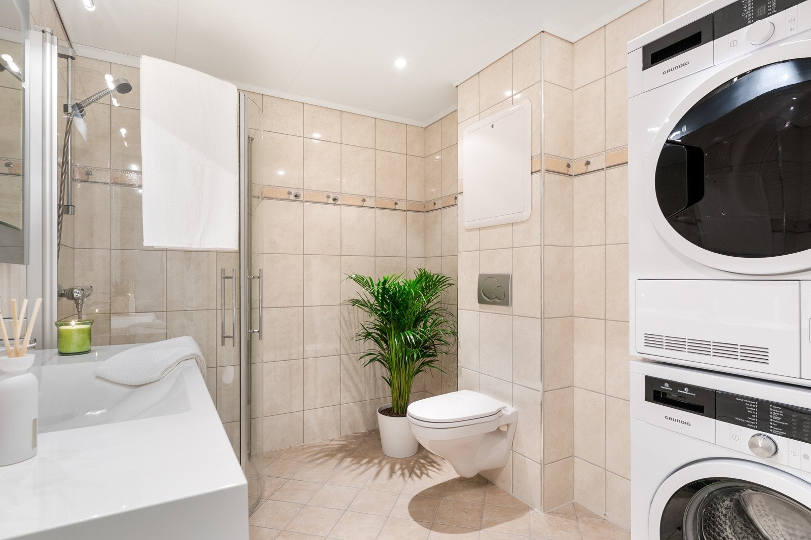 Boligens bad er helfliset og med termostatstyrte varmekabler i gulvet. Her er det opplegg for både vaskemaskin og tørketrommel. Galleribilde