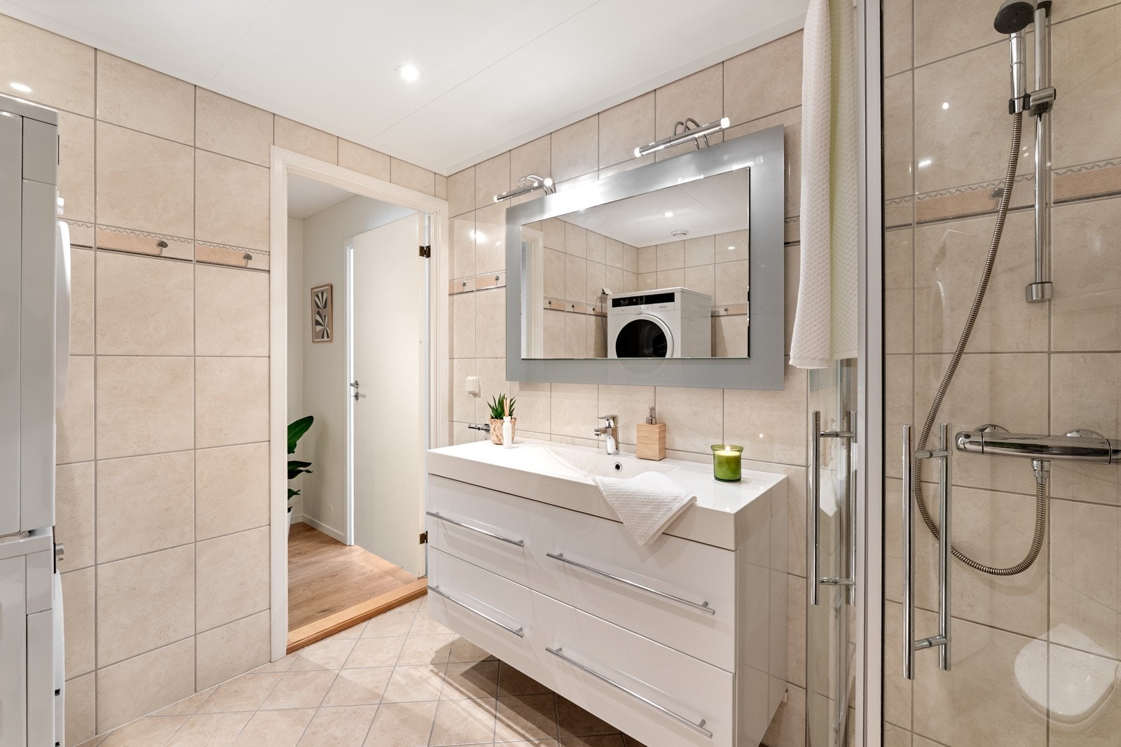 Badet er utstyrt med foldedører i dusj og vegghengt toalett. Galleribilde