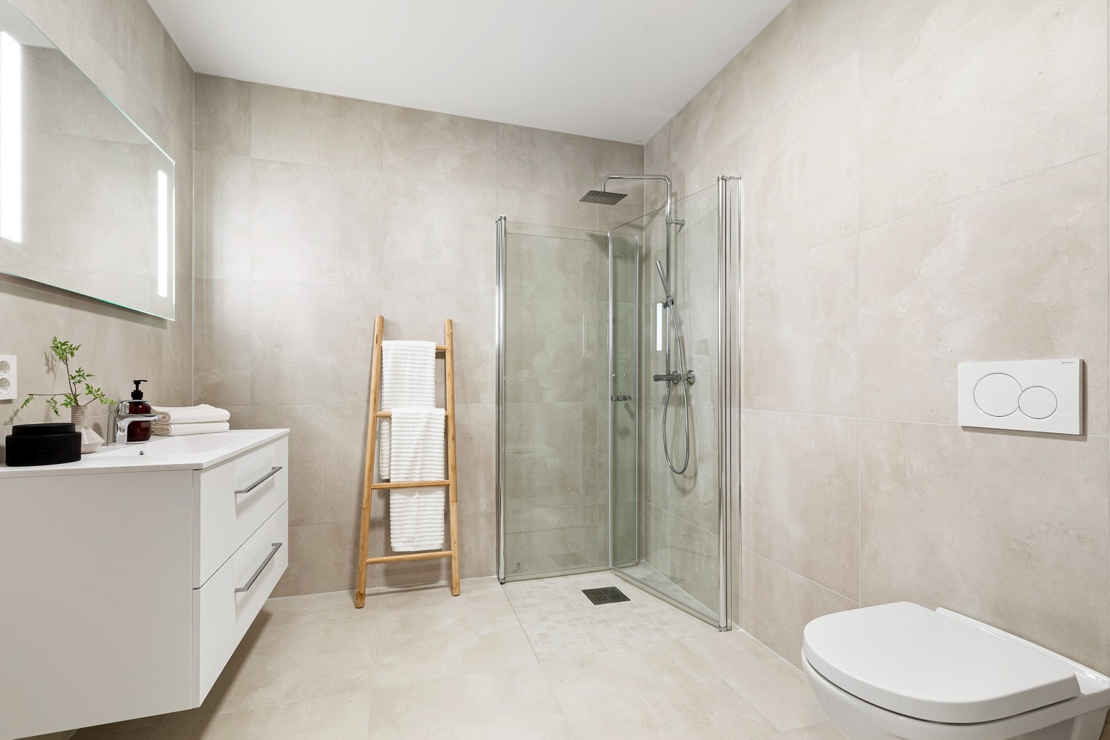 Lekkert bad med dusjhjørne, servant, skuffeløsning og vegghengt toalett. Galleribilde