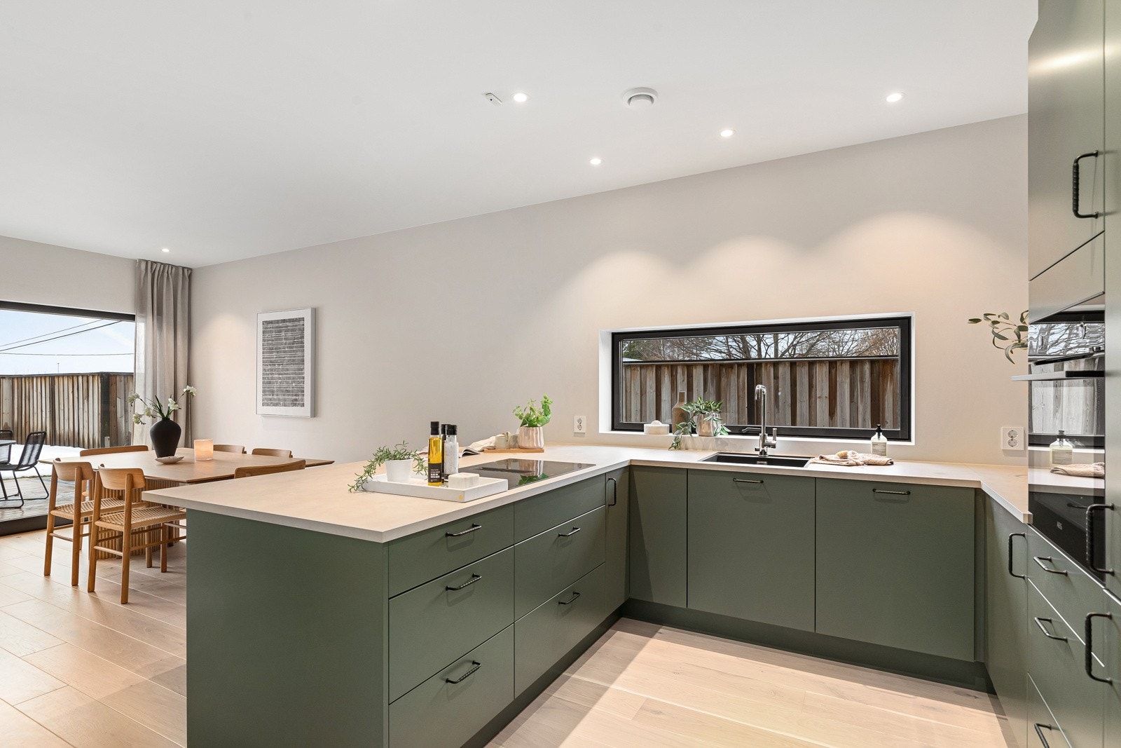 Sosial kjøkkenløsning med utsyn mot stuesone og hage. Galleribilde