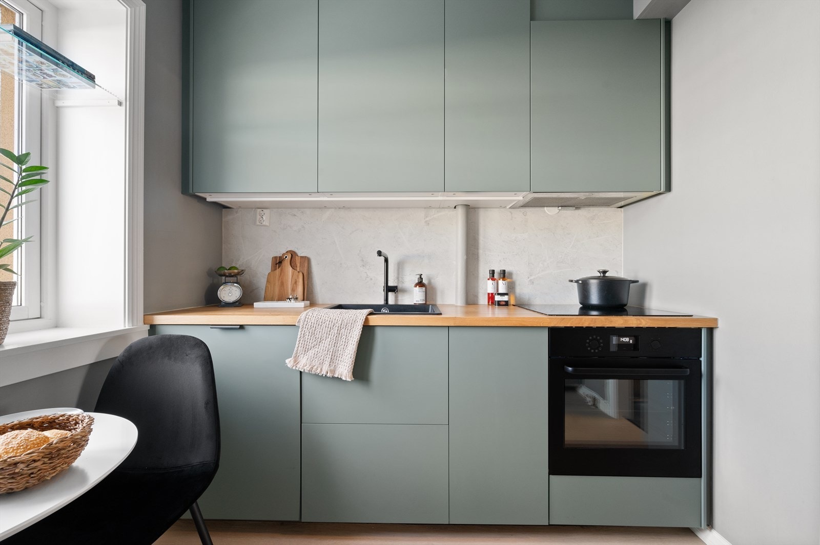 Kjøkkeninnredning med glatte fronter. Laminat benkeplate med nedfelt vask. Integrert platetopp, stekeovn, mikro, oppvaskmaskin og kjøl/ fryseskap. Det er installert kullfilterventilator over kokeplass. Galleribilde