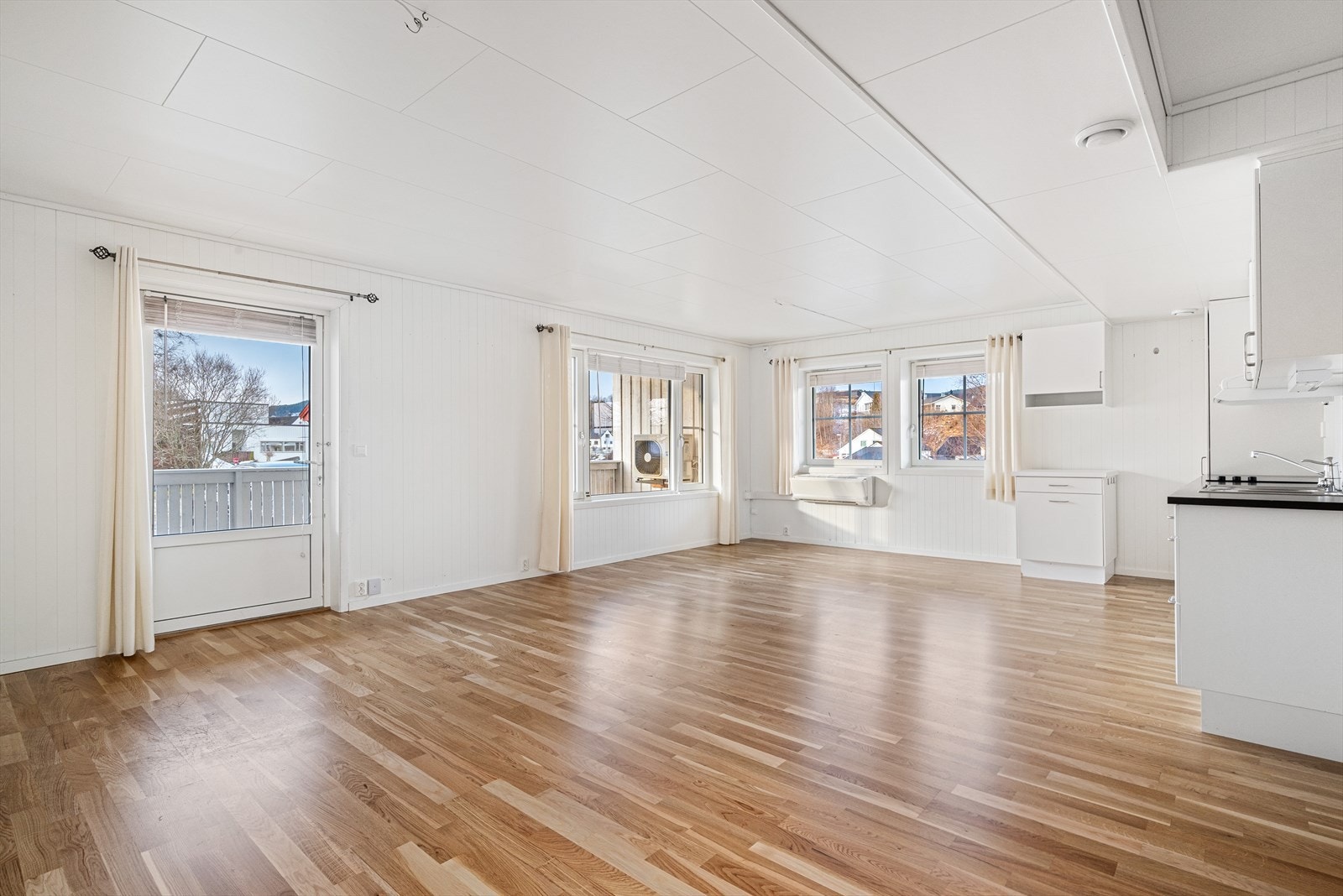 Lys og romslig stue og kjøkken med god plass til både sofagruppe og spisestuemøbler. Galleribilde