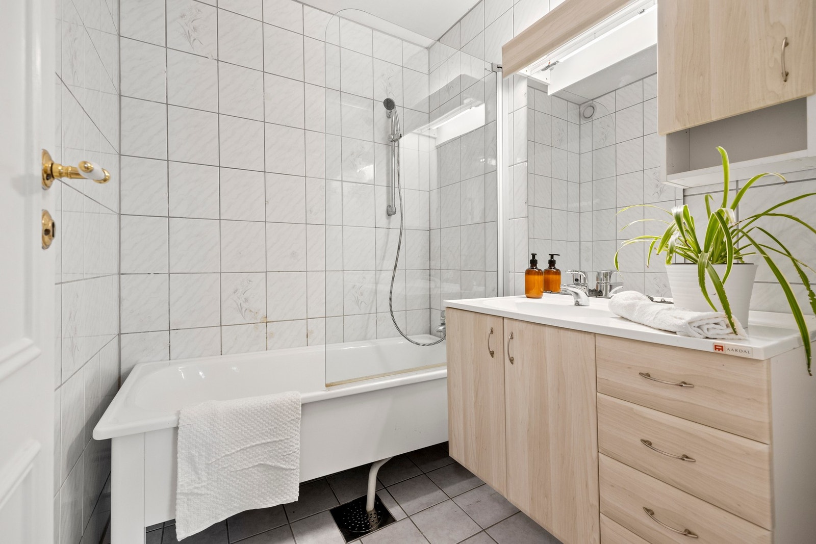 Flislagt bad som inneholder: servant, toalett og badekar med dusjvegg. Galleribilde