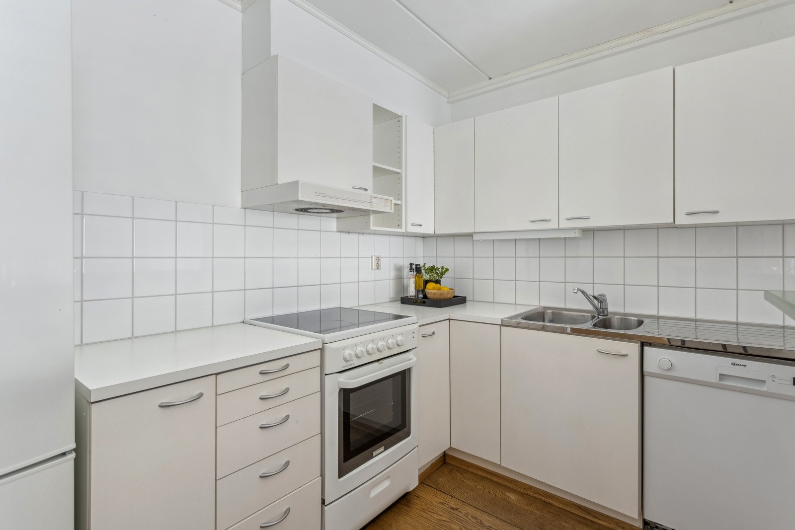 Kjøkkeninnredning med slette folierte fronter og laminat benkeplate med fliser over. Galleribilde