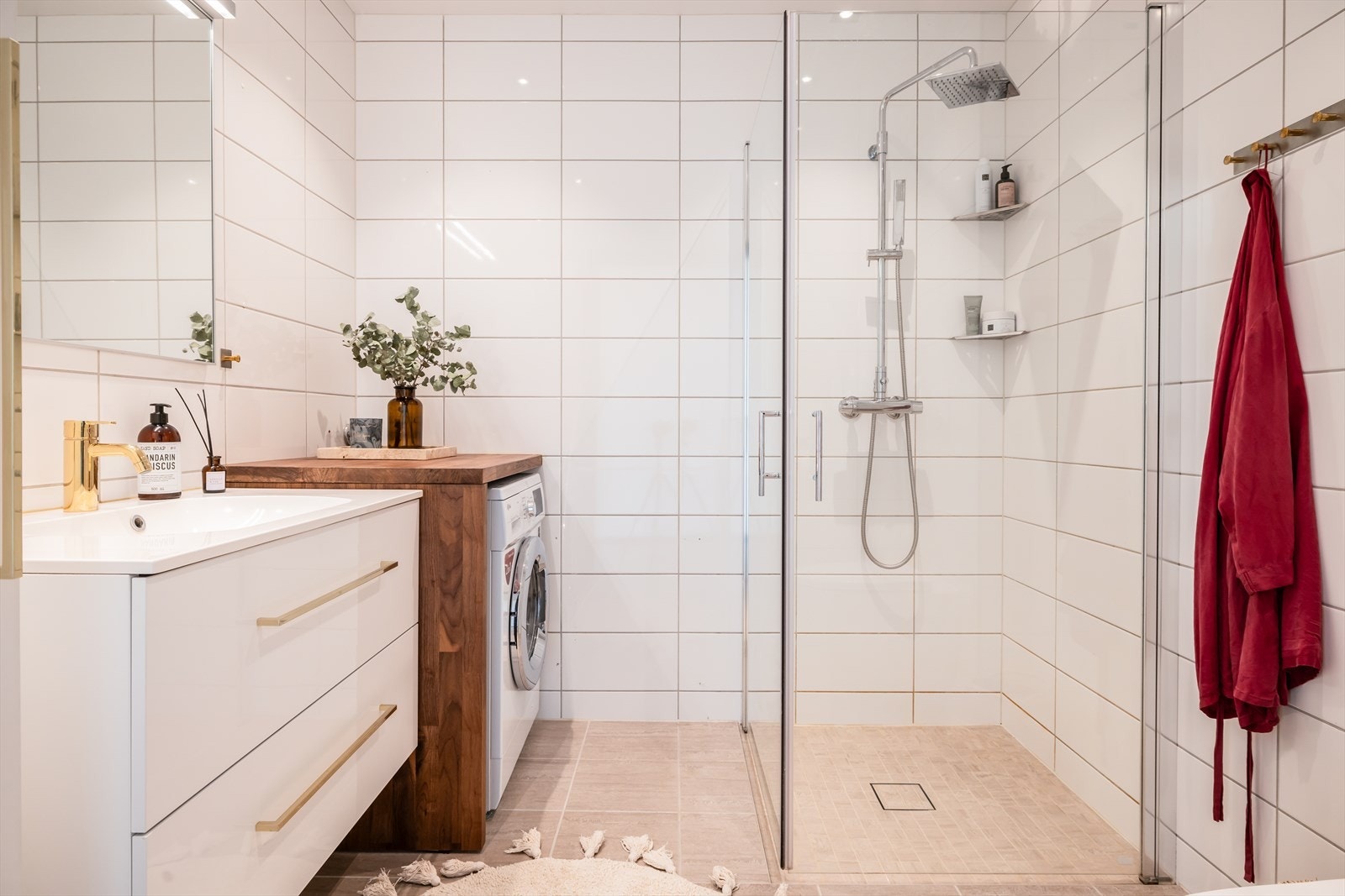 Stilrent helfliset bad med varmekabler i gulv. Baderommet innehar praktisk dusjhjørne og moderne servant i møblement med skuffer. Badet har opplegg for vaskemaskin og tørketrommel. Galleribilde