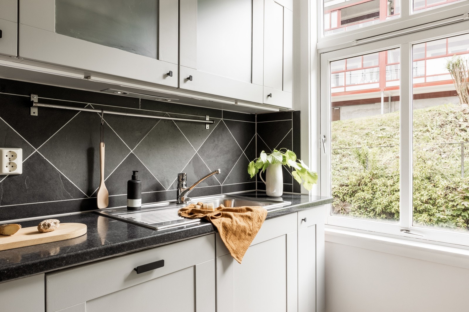 Pen kjøkkeninnredning med profilerte fronter, to glasskap og laminat benkeplate med nedfelt vask av stål. Galleribilde