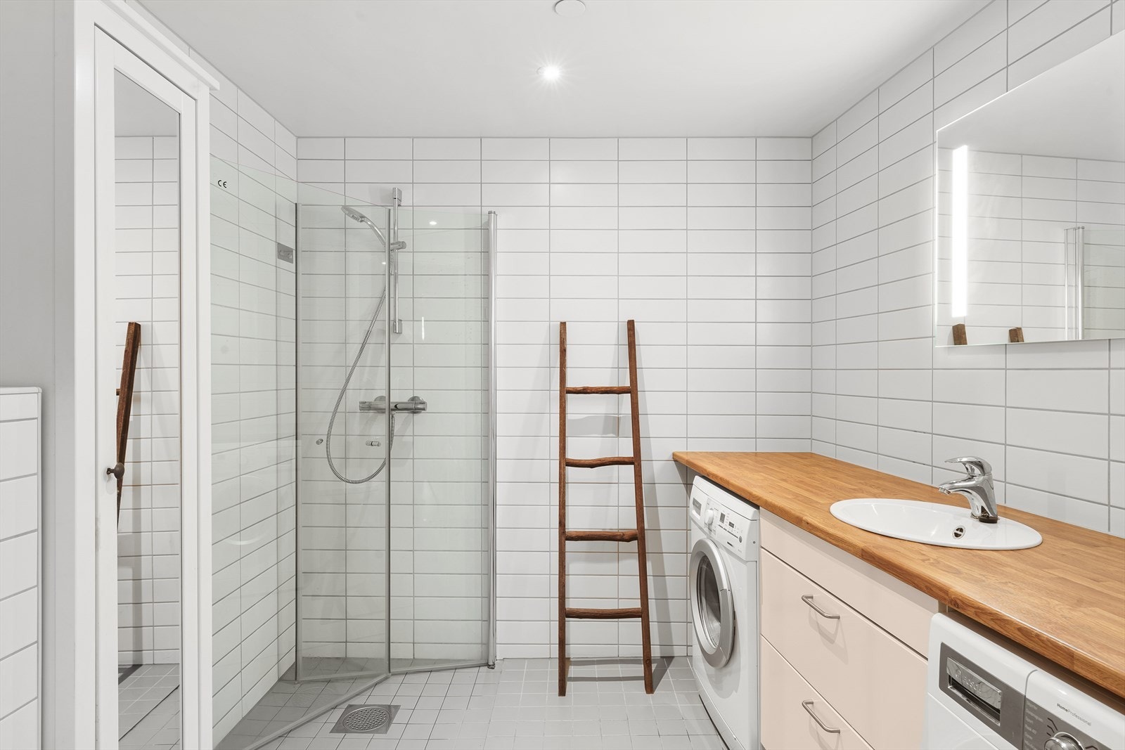 Moderne og pent bad med opplegg for både vaskemaskin og tørketrommel under benkeplate. Galleribilde