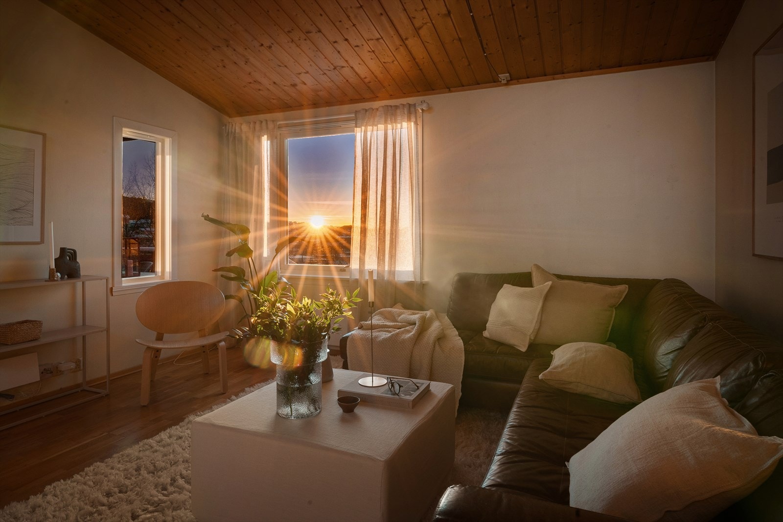 Solrik stue med store vindusflater som slipper inn naturlig lys, skaper en varm og innbydende atmosfære. Galleribilde