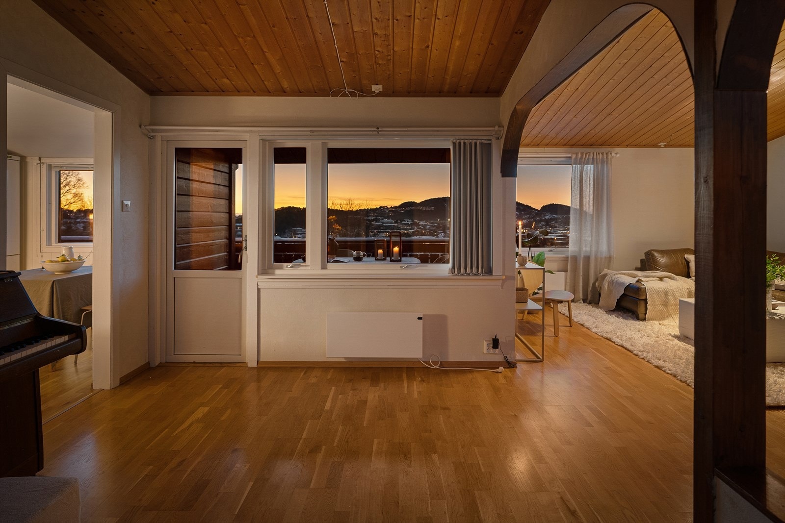 Opplev en lys og romslig stue med store vinduer som rammer inn en vakker solnedgang og nydelig utsikt over nabolaget Galleribilde