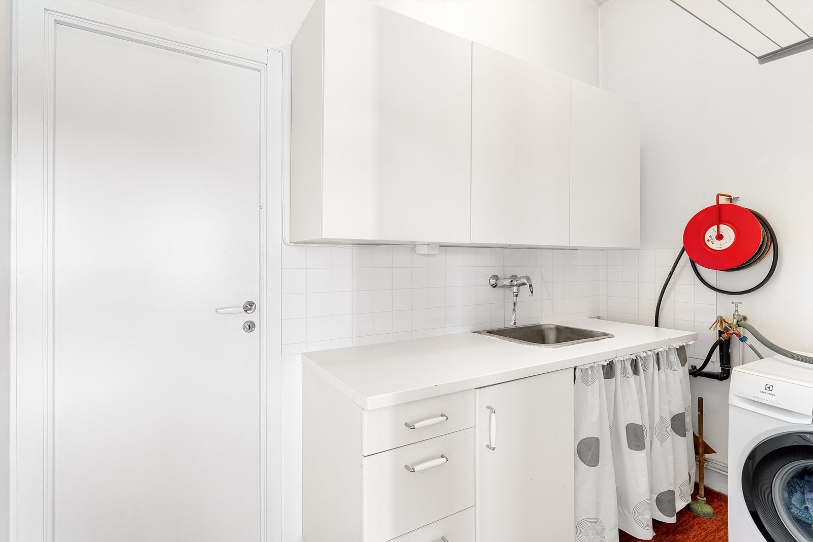 Funksjonelt vaskerom med praktisk benk, skapplass, og vask. Ideell for enkel klesvask og organisering. Galleribilde