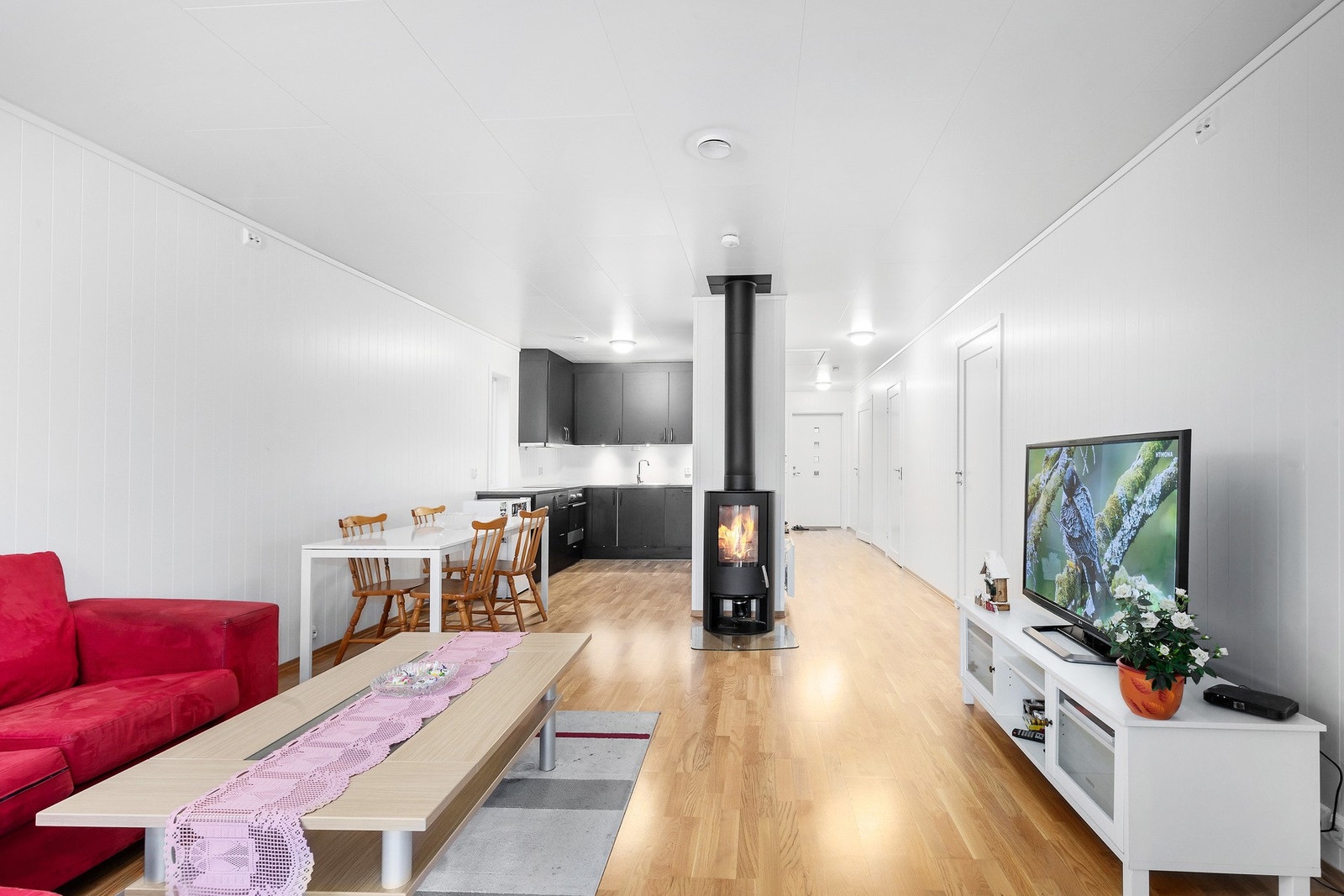 Det er parkett på gulv, panelplater på vegger og montert vedovn på stue. Galleribilde