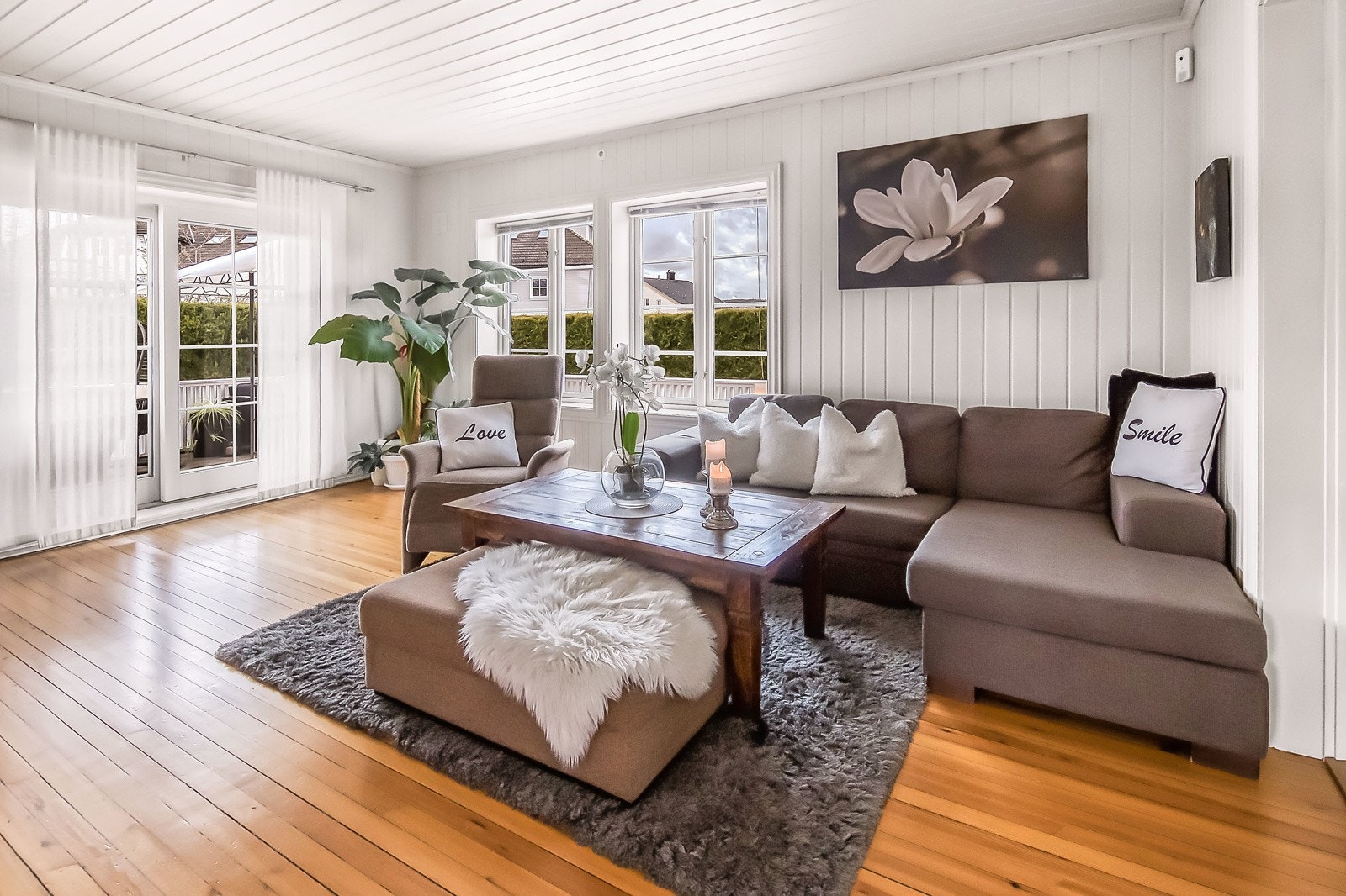 Lys og innbydende stue med store vindusflater som gir godt lys inn i rommet Galleribilde