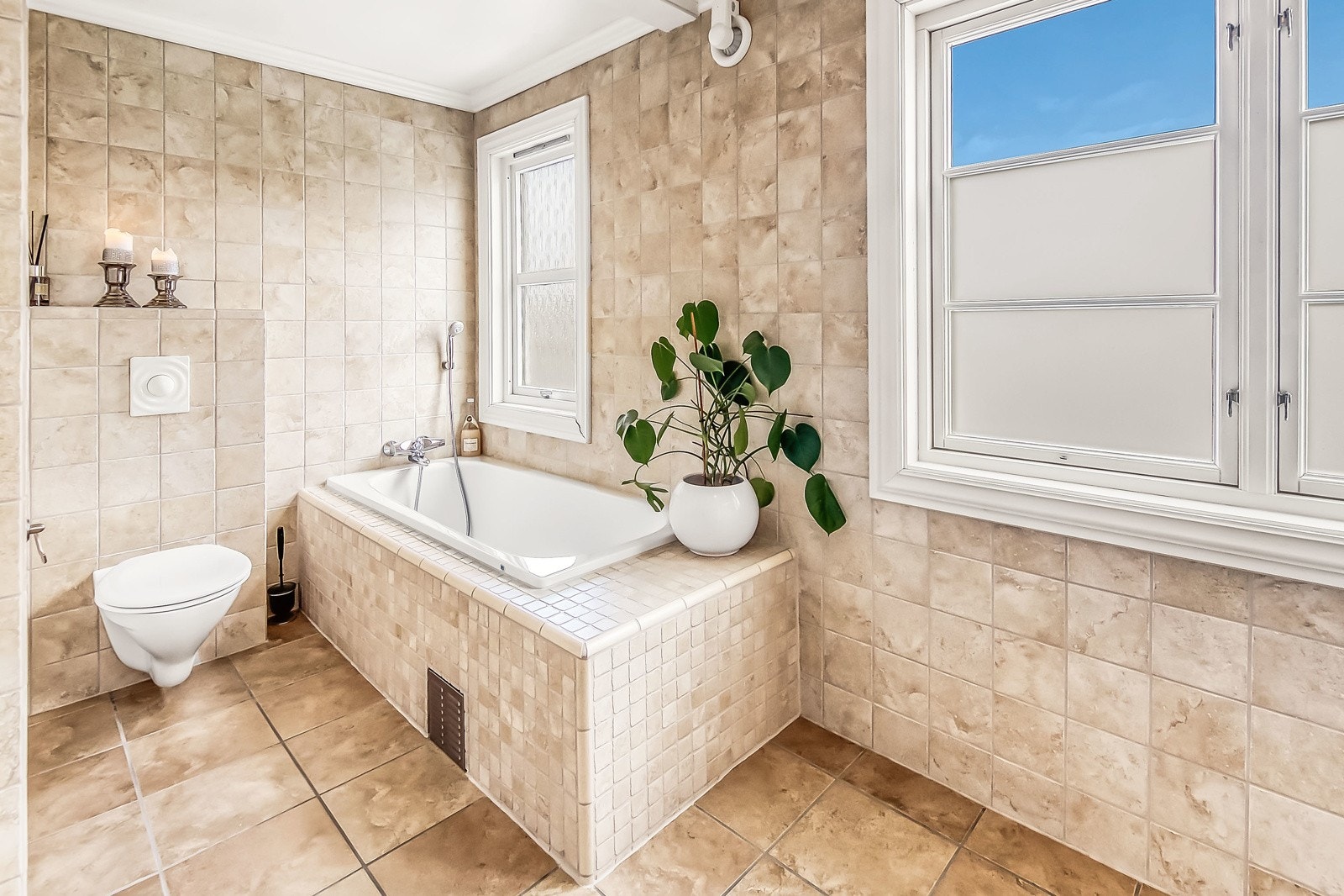 Badet inneholder både badekar, dusjkabinett, vegghengt toalett og servant i romslig innredning Galleribilde