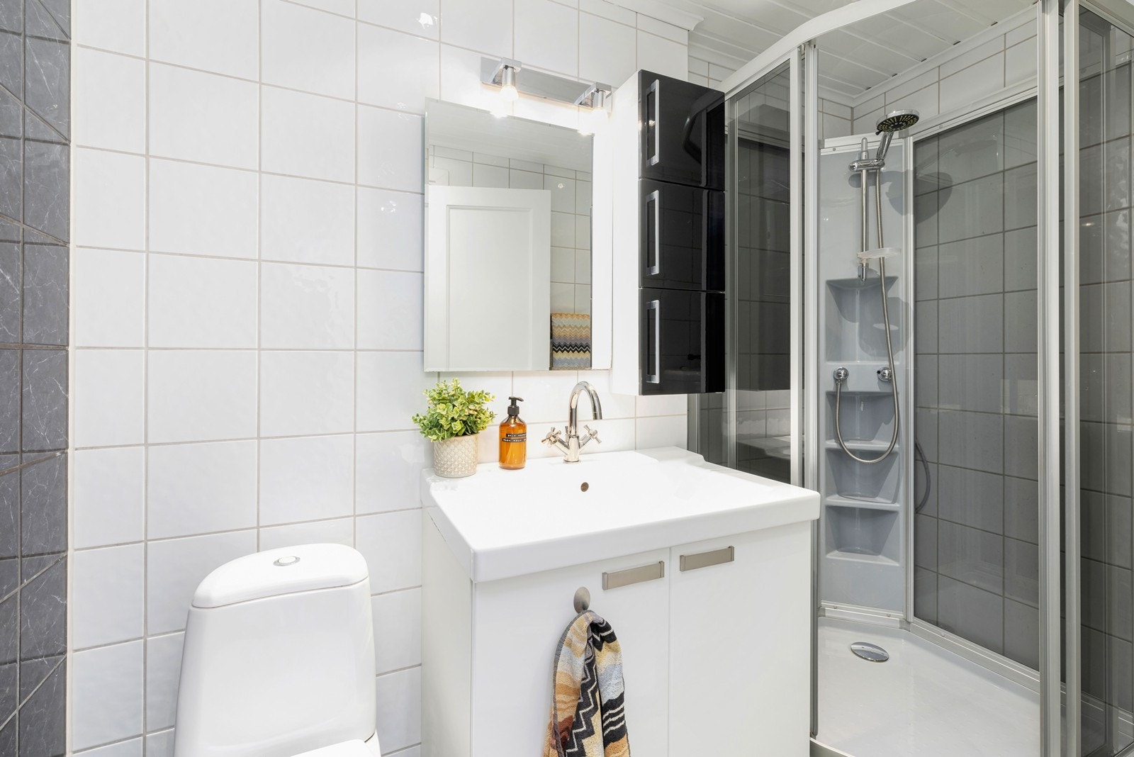Flislagt bad med varmekabler i gulv. Badet har dusjkabinett, toalett og servant med underskap og overspeil. Galleribilde