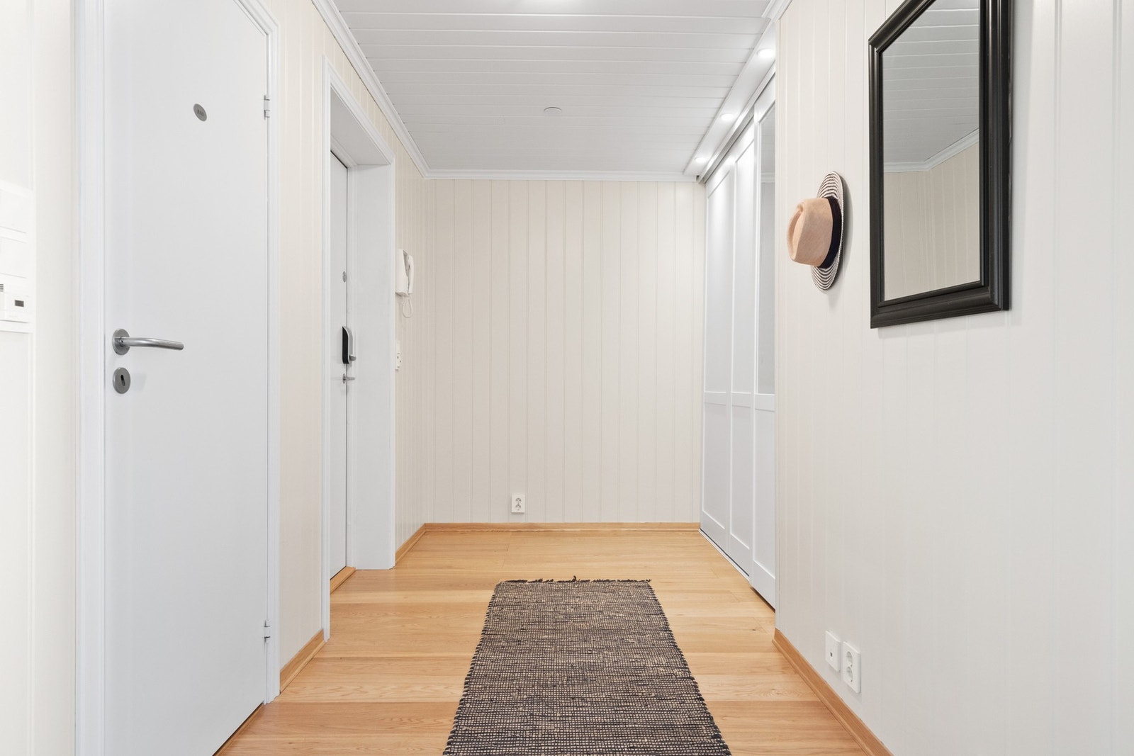 Entreen har 1-stavs parkettgulv og lysmalte panelplater på veggene. Galleribilde
