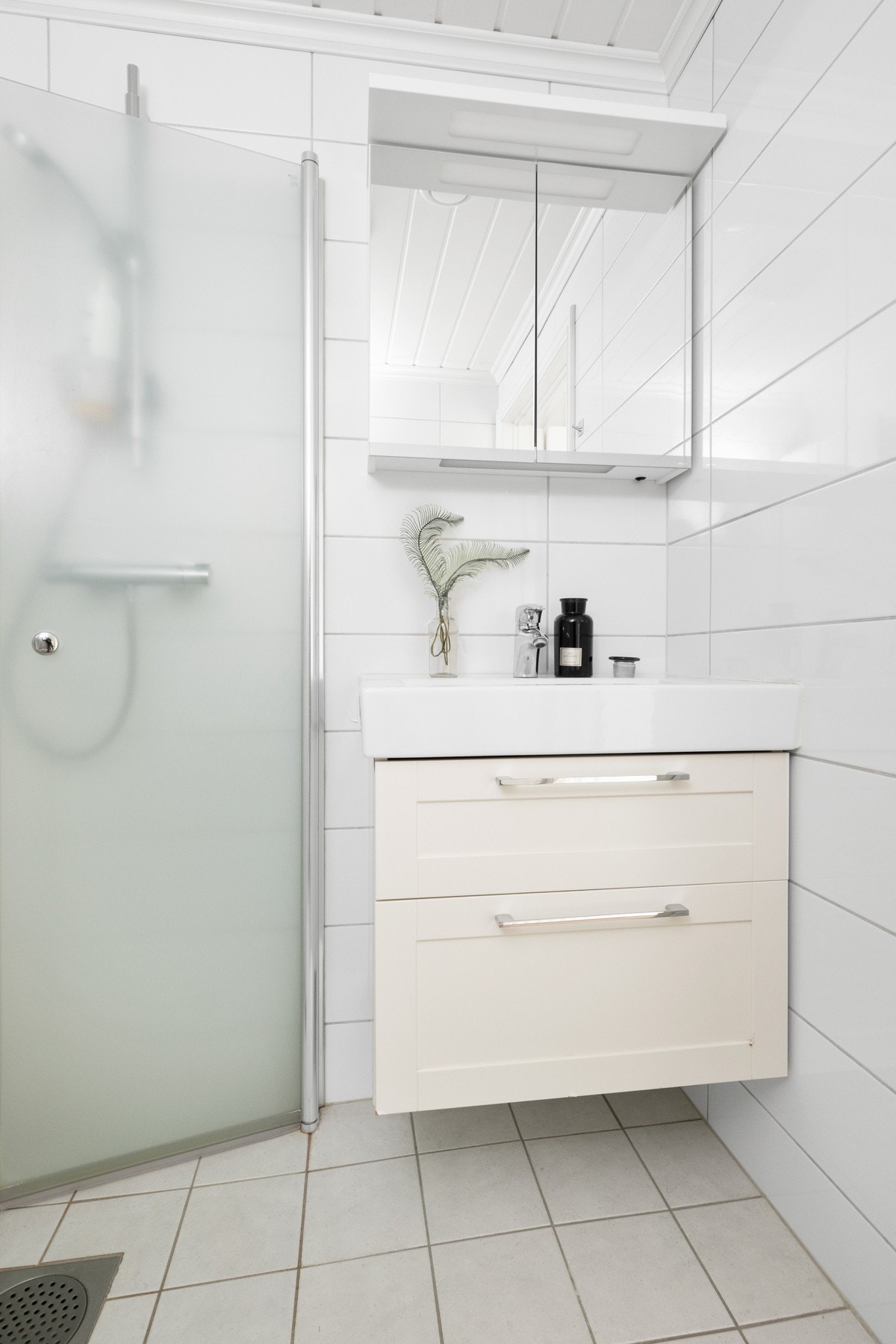 Den øvrige innredningen består av en servant med lyse skuffer, et hvitt veggskap og et speilskap med belysning. Galleribilde