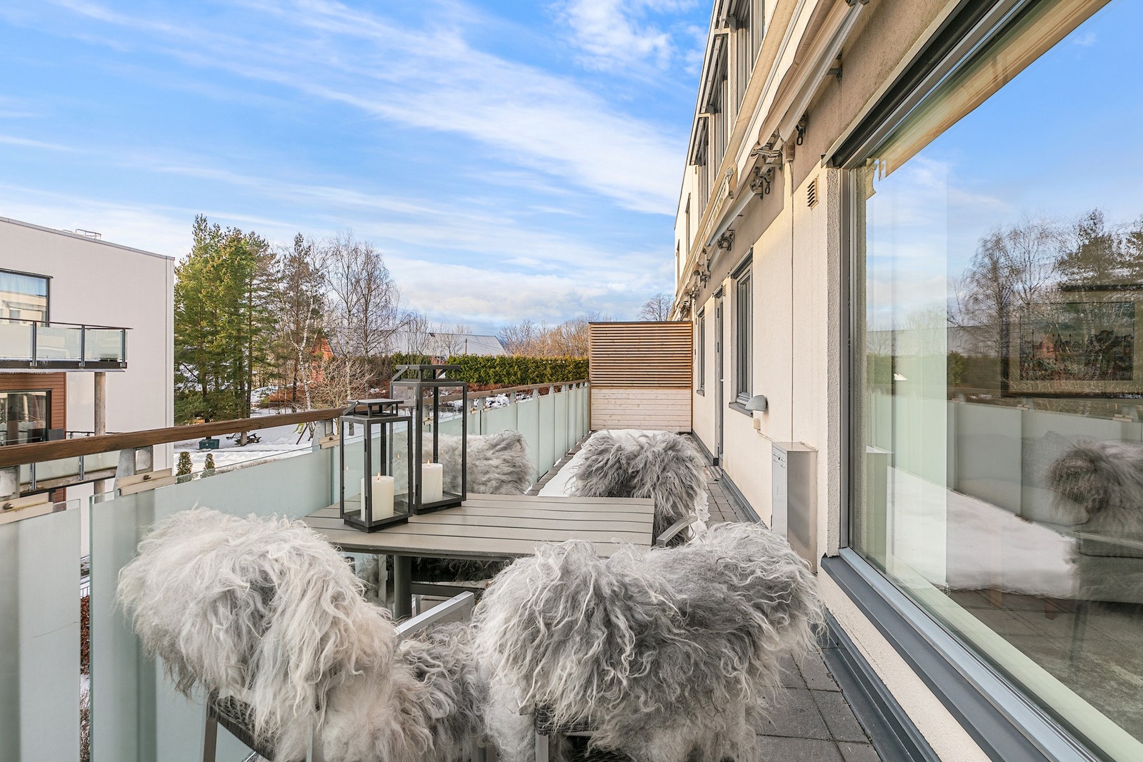 Den langsgående balkongen har bruksunderlag med fliser og rekkverk i stål, glass og tre Galleribilde