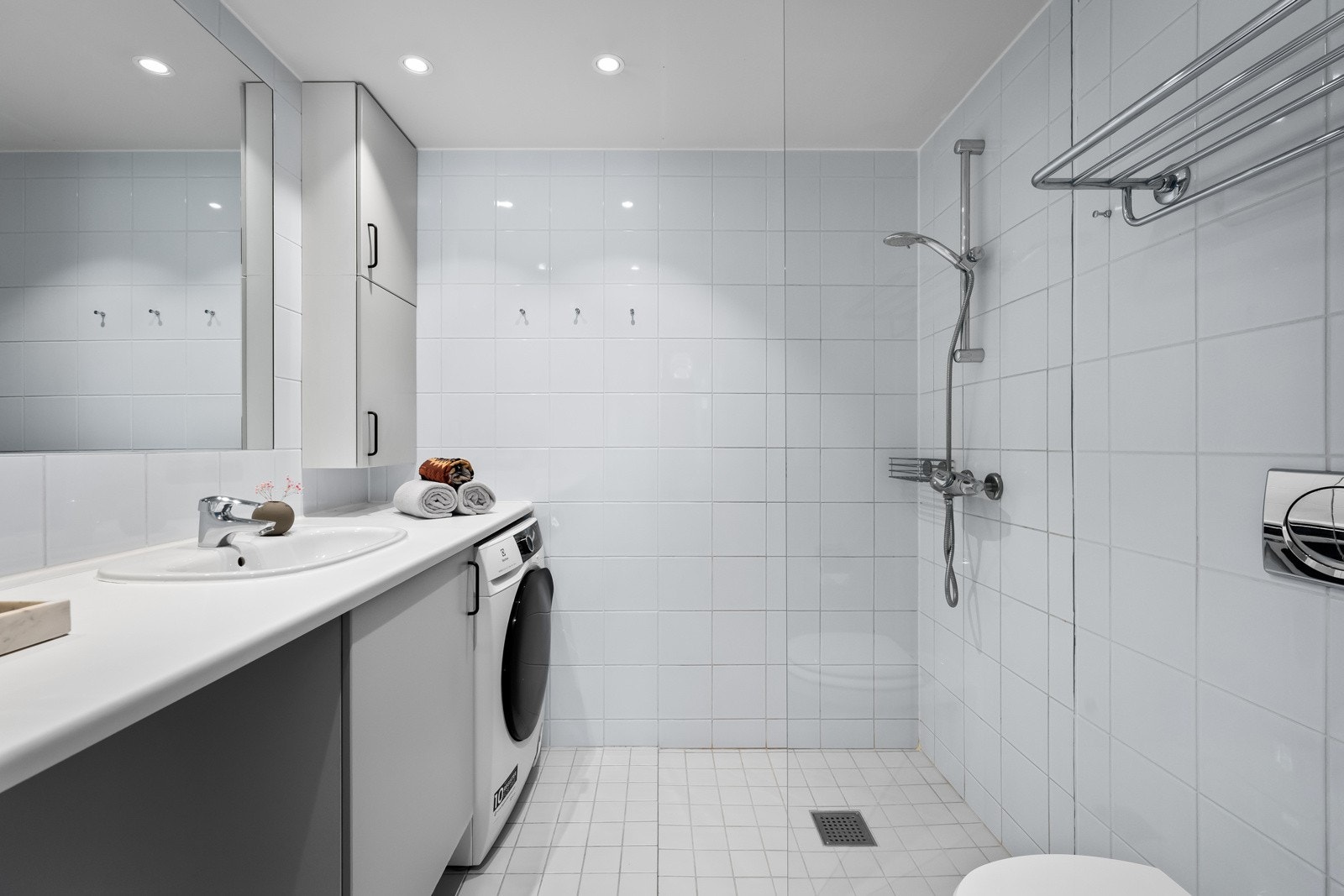 Badet er fra 2005 med flislagte gulv og vegger i lyse toner Galleribilde