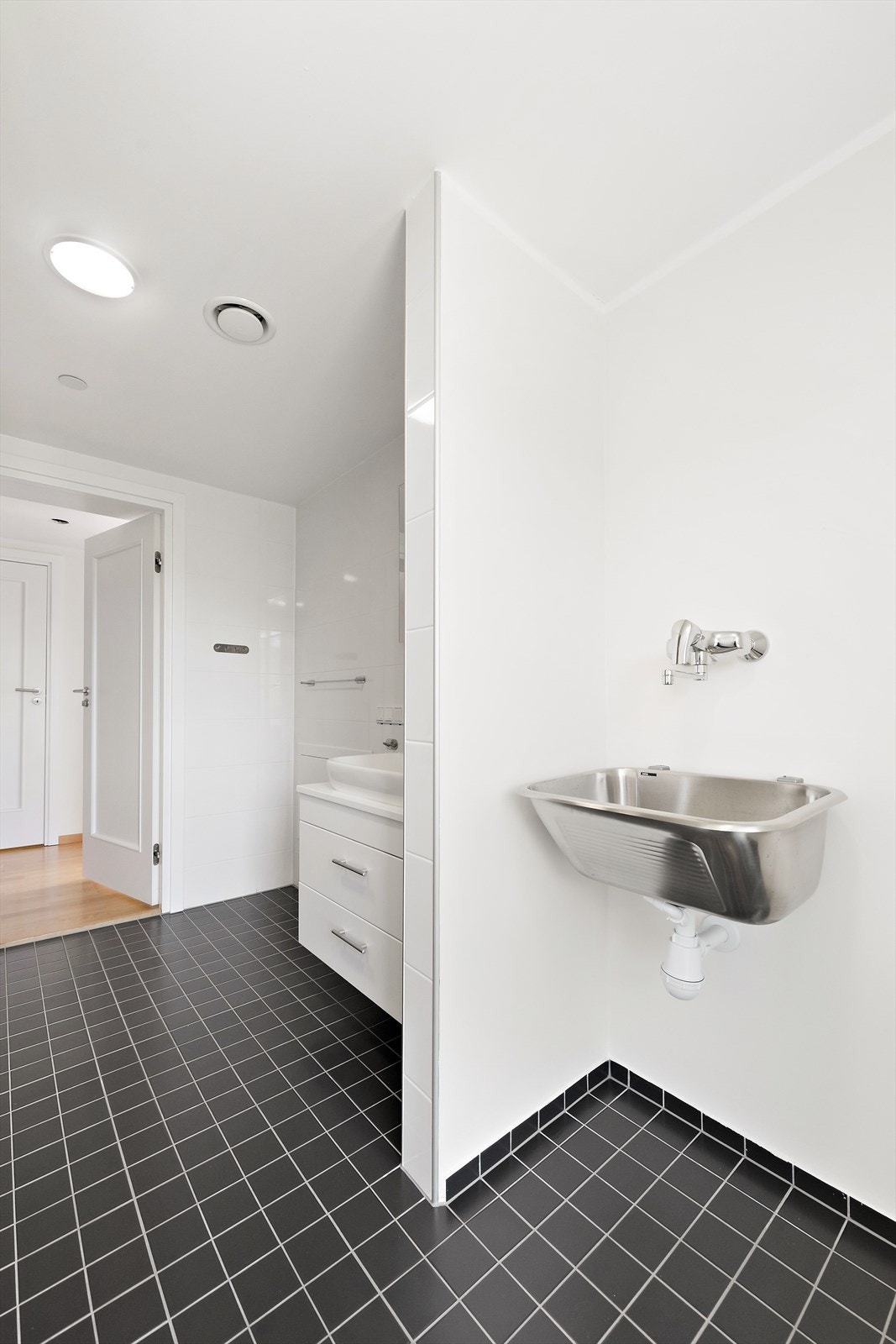 Vaskeromsdelen er utstyrt med skyllekar og opplegg for vaskemaskin mens badet er utstyrt med baderomsinnredning, toalett og dusjvegger/hjørne. Galleribilde