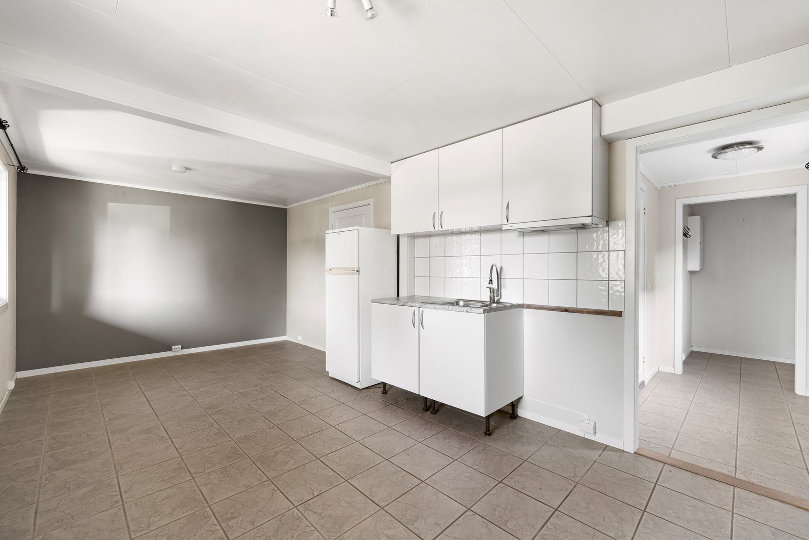 Stue med kjøkkeninnredning er etablert i det som opprinnelig var to store soverom i underetasjen. Her er det varme i gulvet. Galleribilde