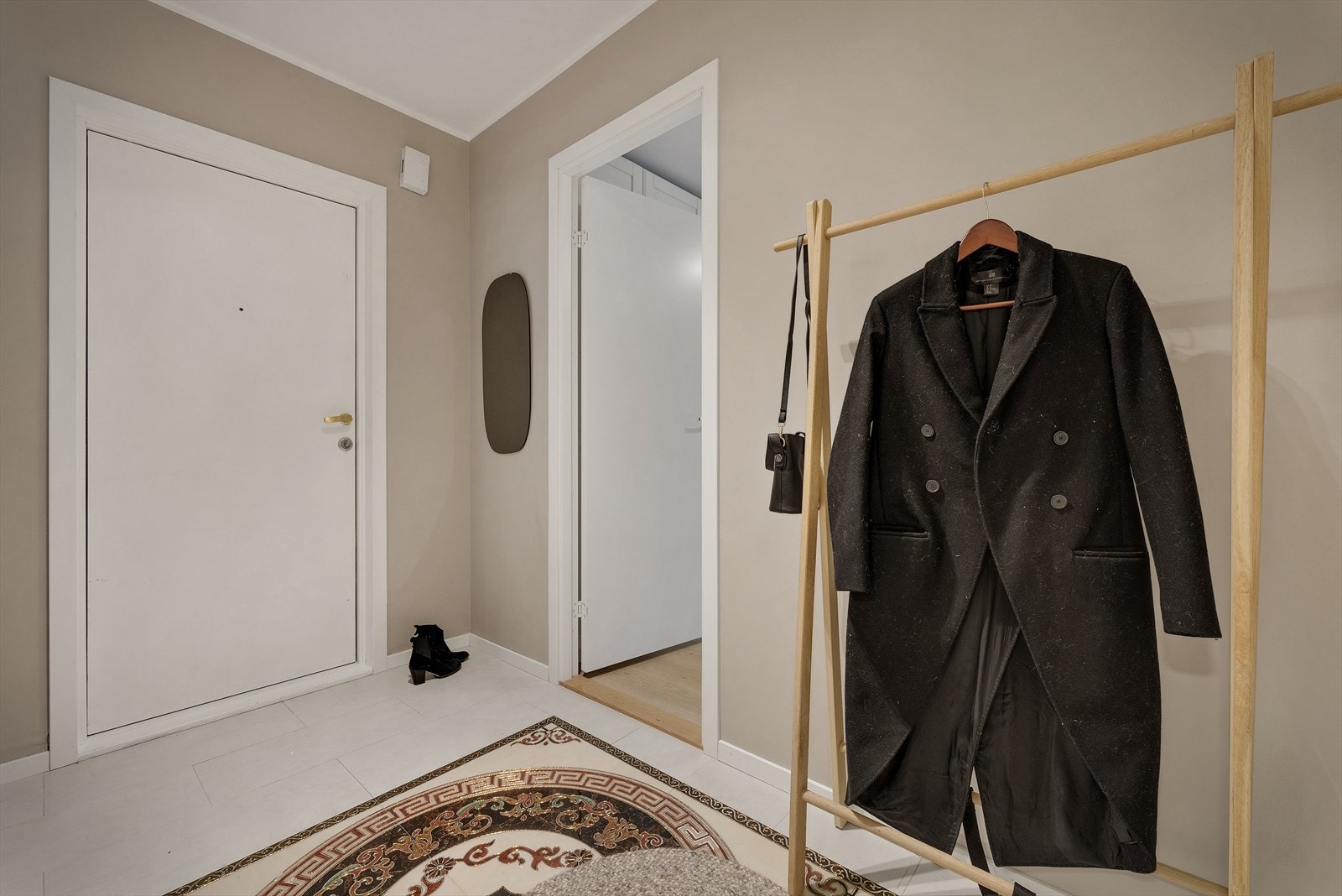 En blir ønsket velkommen inn i en lekker entre med flislagt gulv og god plass til å henge fra seg yttertøy Galleribilde