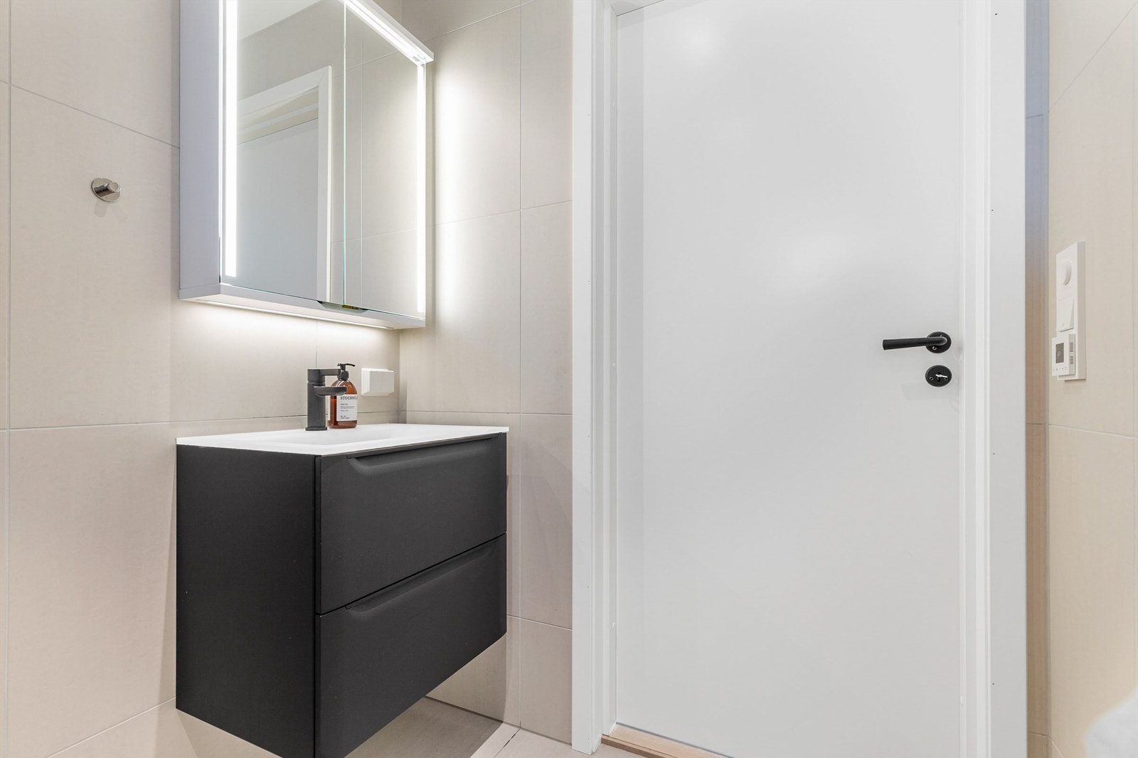 Vegghengt servantskap med ovenpåliggende servant og ett-greps armatur. Speilskap med integrert belysning og stikkontakt over servant. Galleribilde