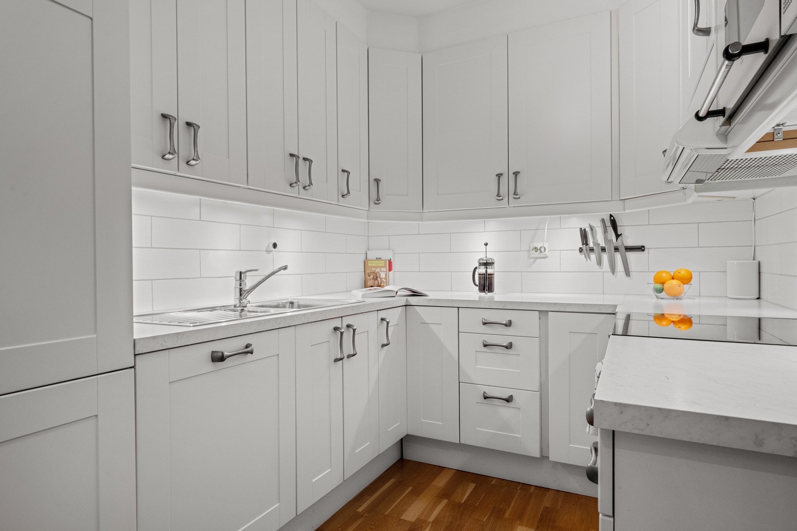 Pen kjøkkeninnredning med hvite profilerte fronter og laminat benkeplate. Galleribilde